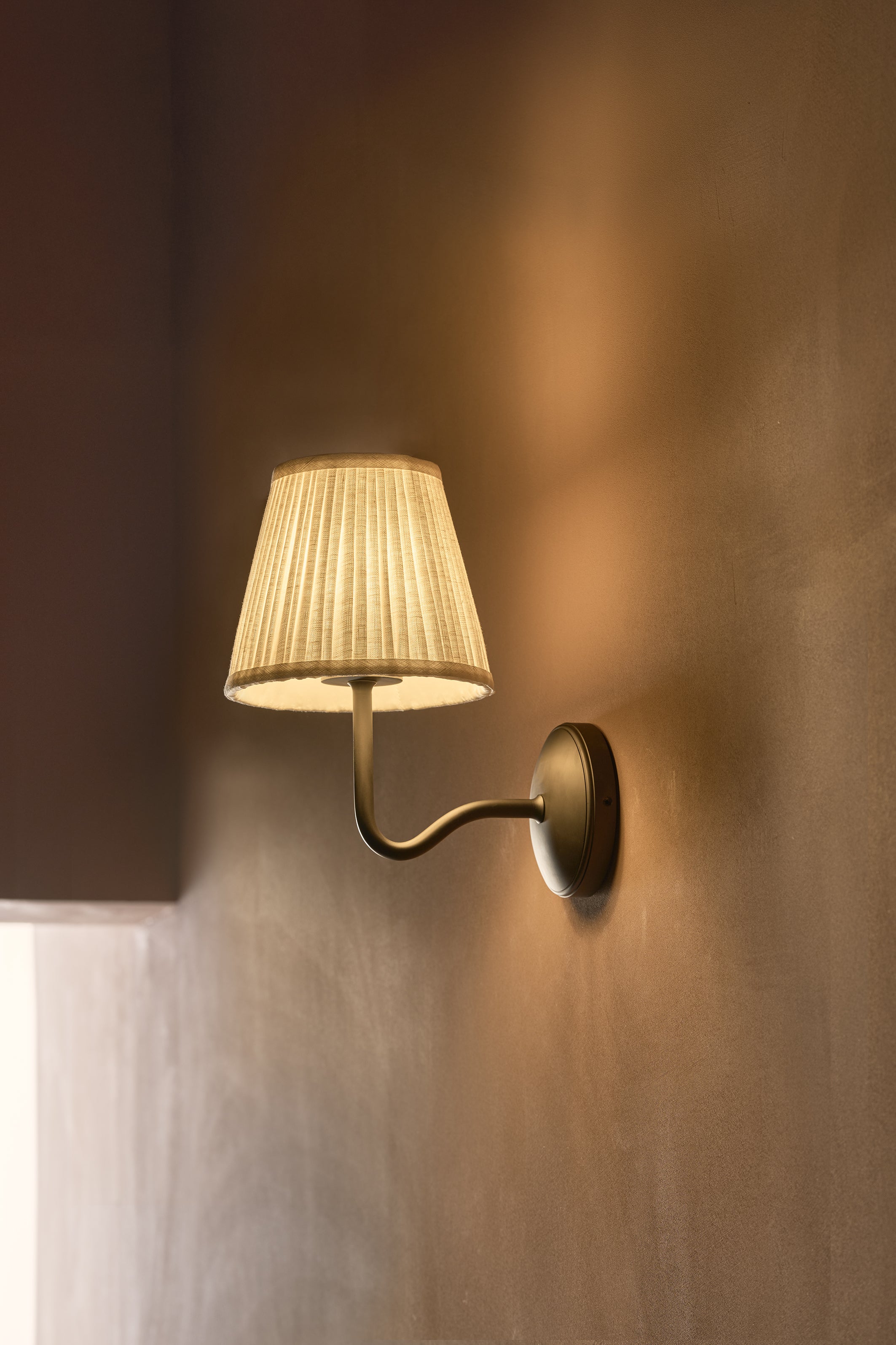 Malvern Medium Wall Light in Alabaster White with bronze finish, wall-mounted and illuminated.