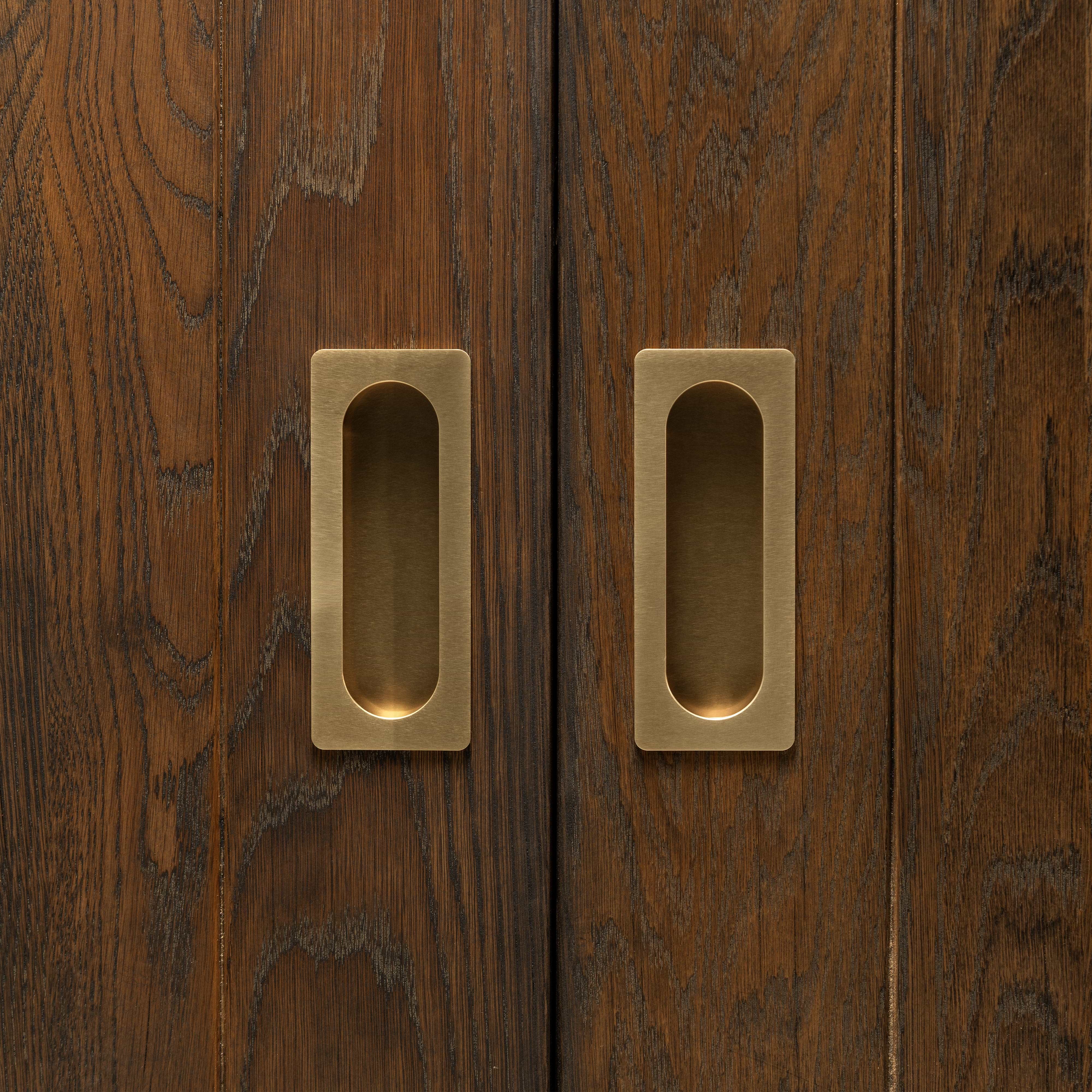 Regent Recessed Medium Pull in antique brass installed on dark wooden sliding doors, showing handle detail.