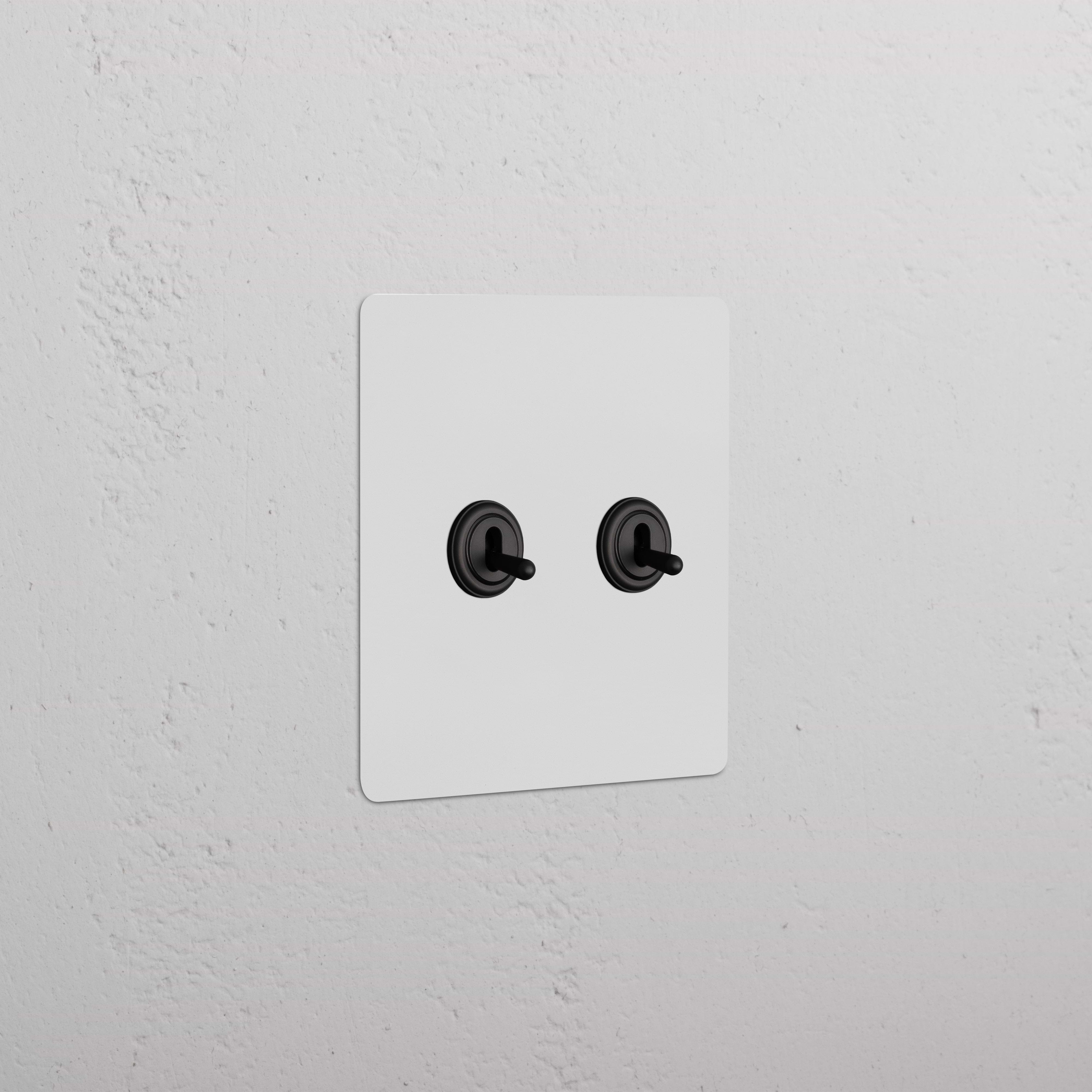 Kew 2G Toggle Switch - Paintable Bronze, wall-mounted with two central toggles and a customizable bronze finish.
