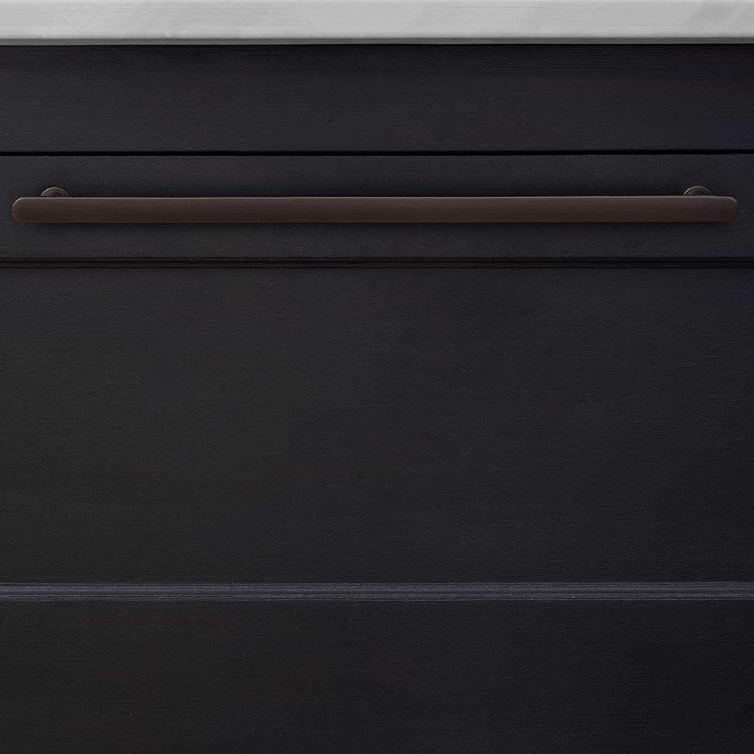 Large bronze Milliner furniture handle mounted horizontally on a dark cabinet below a light countertop.