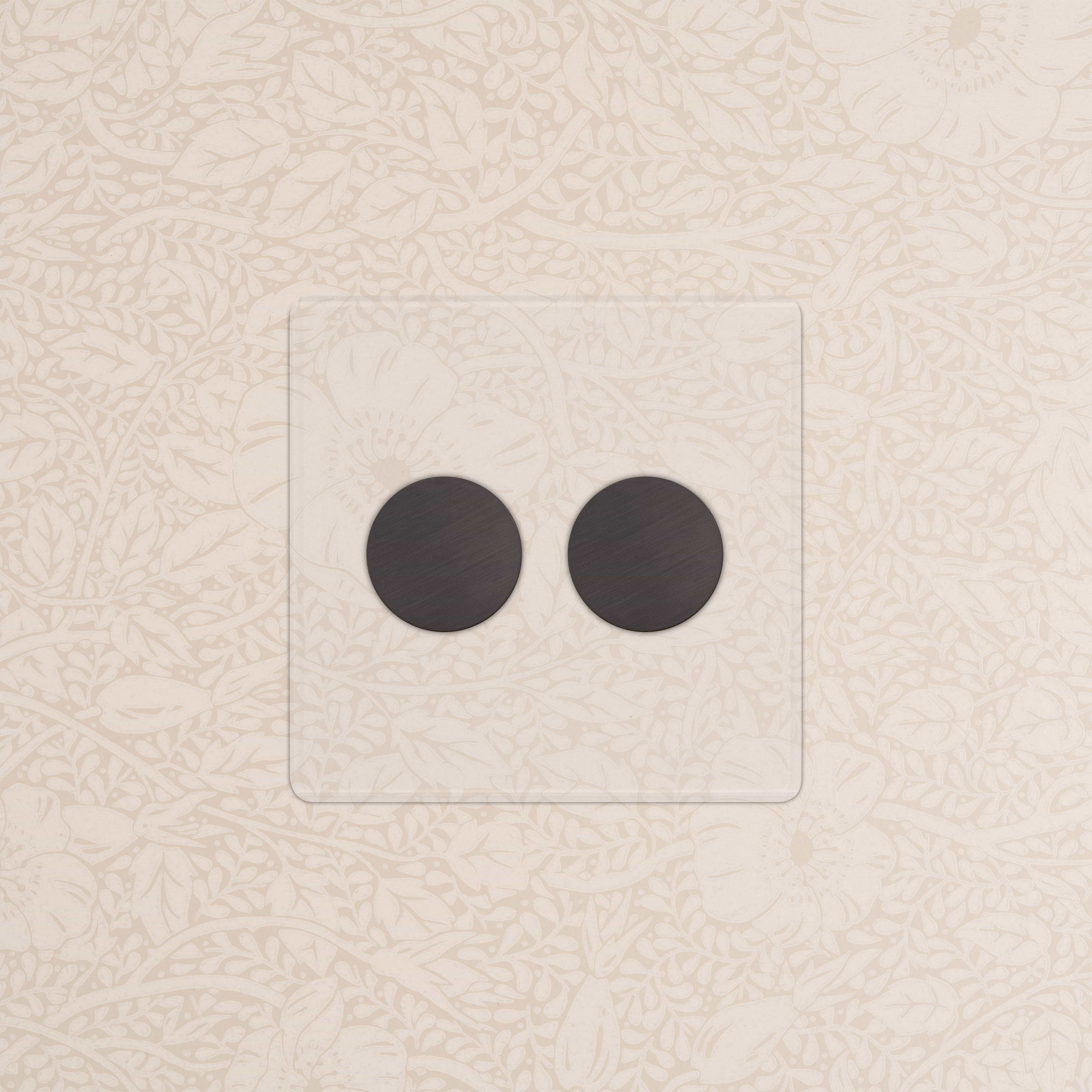 Kew 2G Dimmer Switch in clear bronze finish with two round black dimmer knobs on a floral-patterned wall.