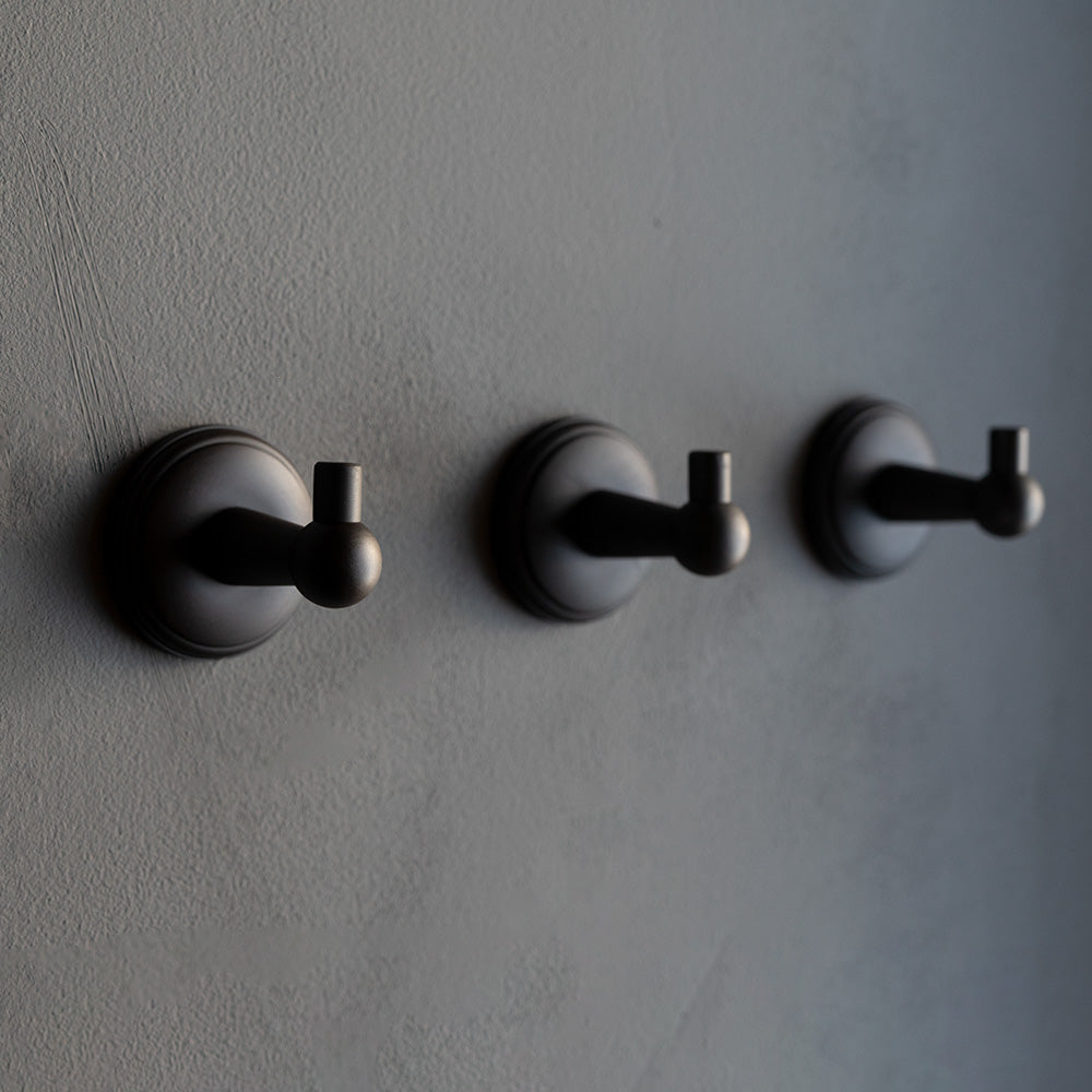 Hyde Hook in bronze finish with a round base and modern design, mounted on a gray wall.