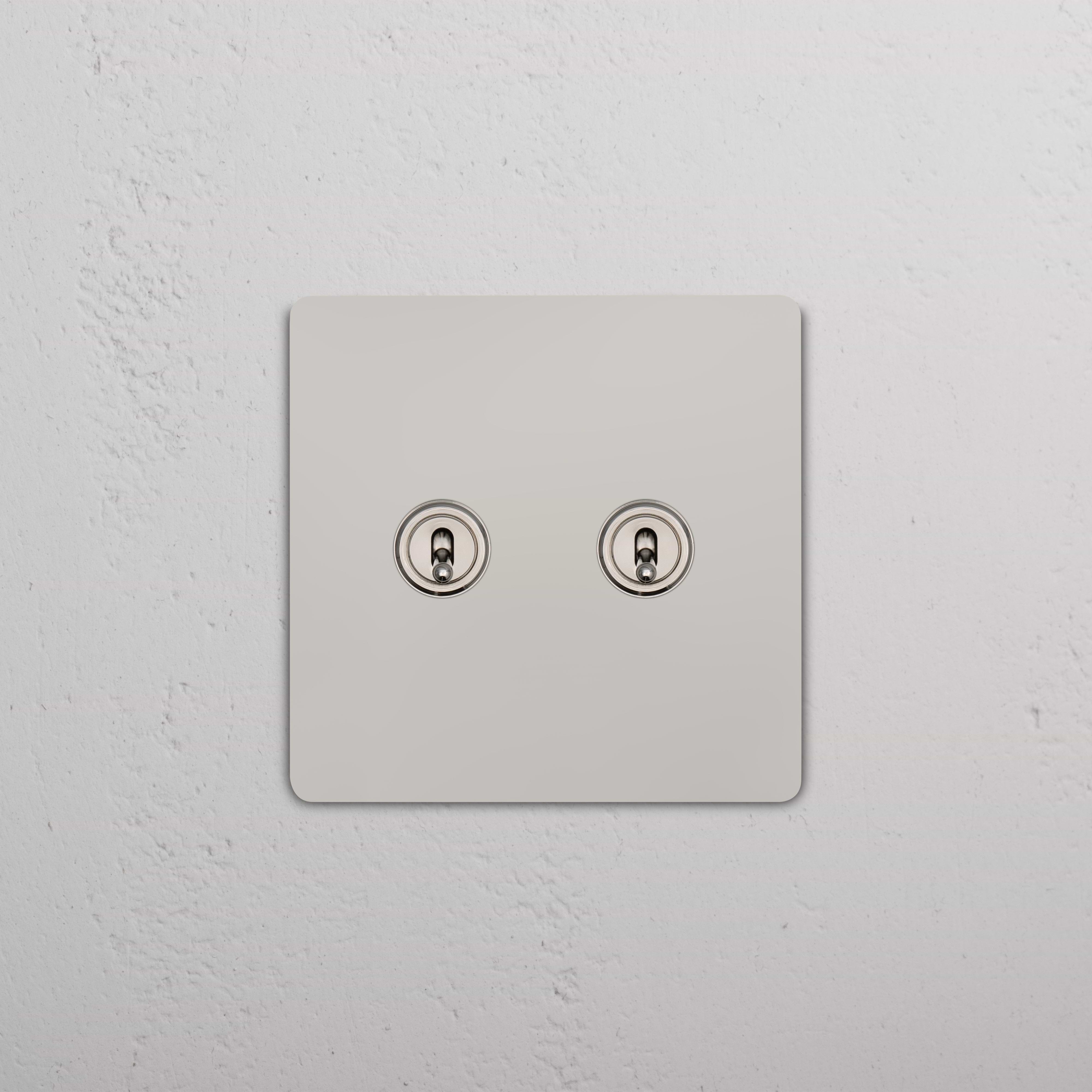 Grove 2G Toggle Switch in polished nickel with two metallic toggles, shown installed on a wall.