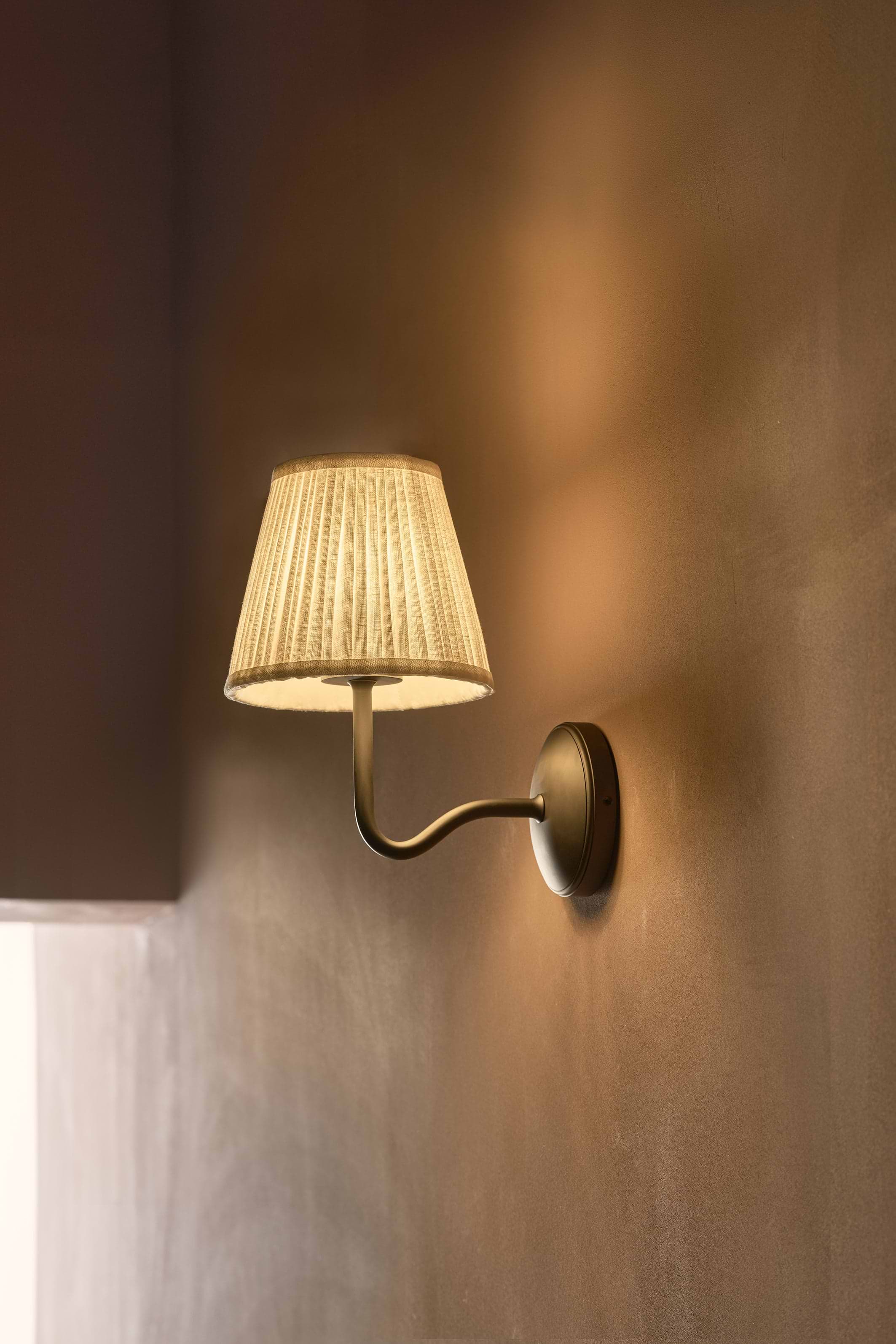 Malvern Medium Wall Light in Alabaster White with bronze finish, wall-mounted and illuminated.