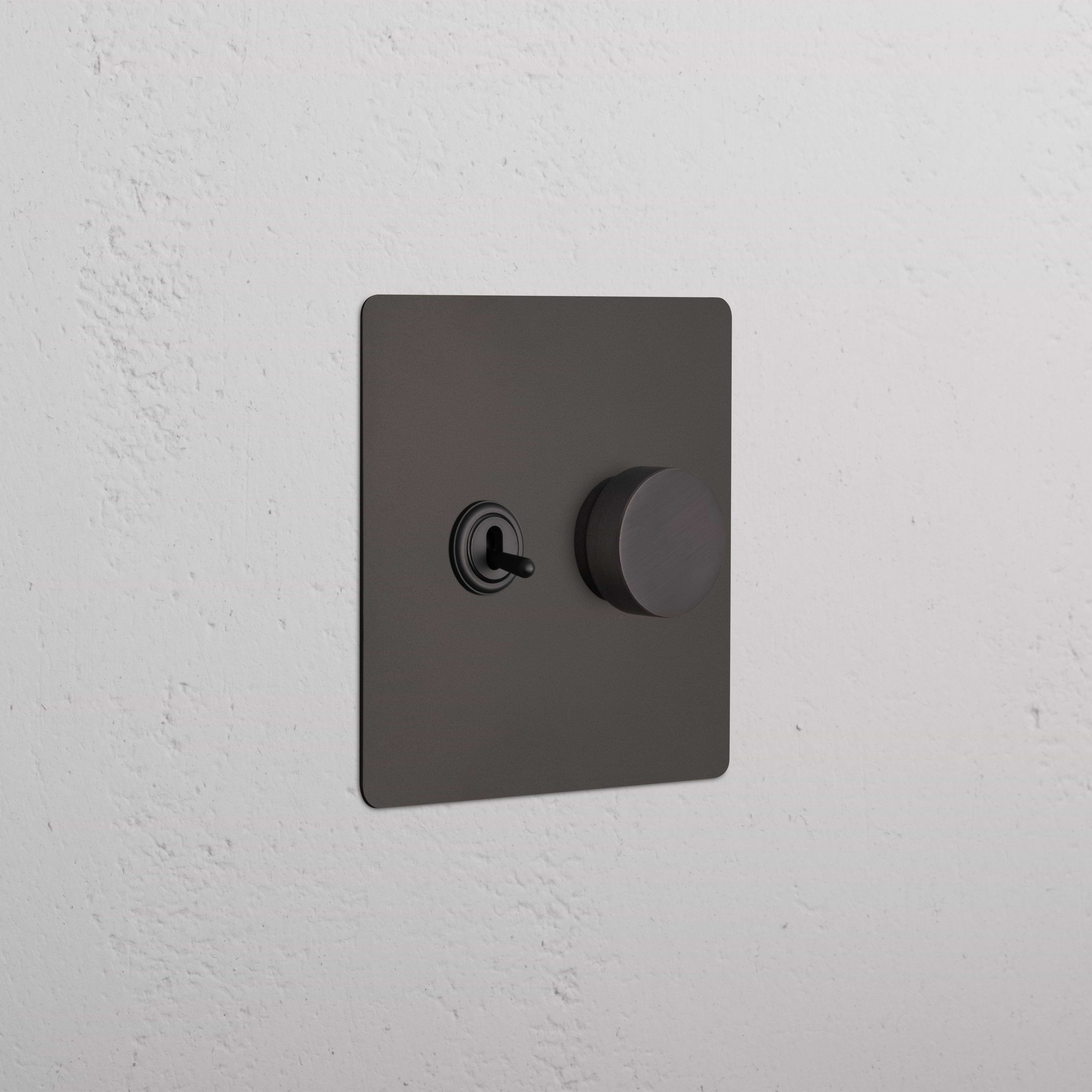 Bronze Kew 2G Toggle & Dimmer Switch with left toggle and right dimmer knob, shown on a white wall.