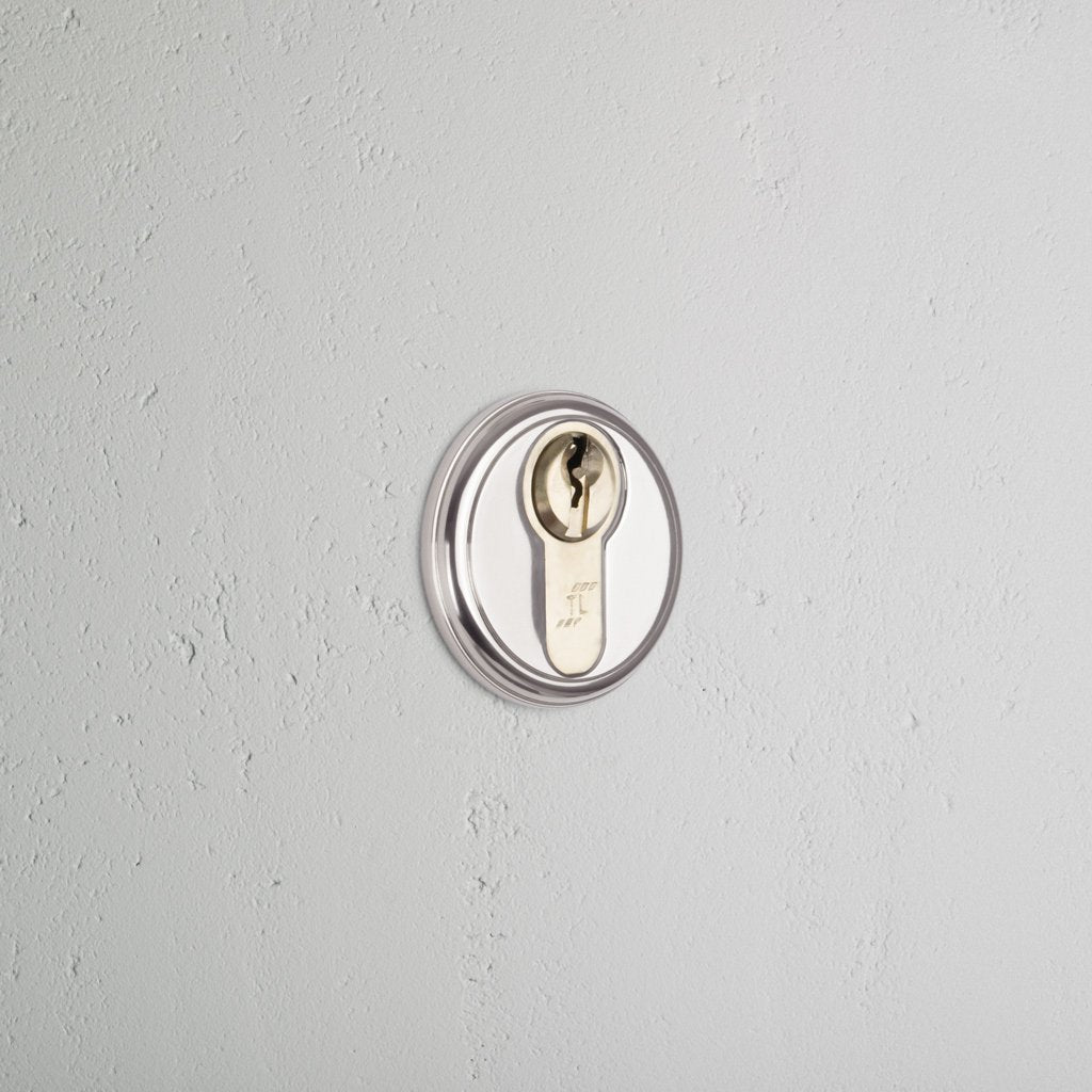 Canning Key Escutcheon in polished nickel, installed on a light gray wall, showing its circular key slot.