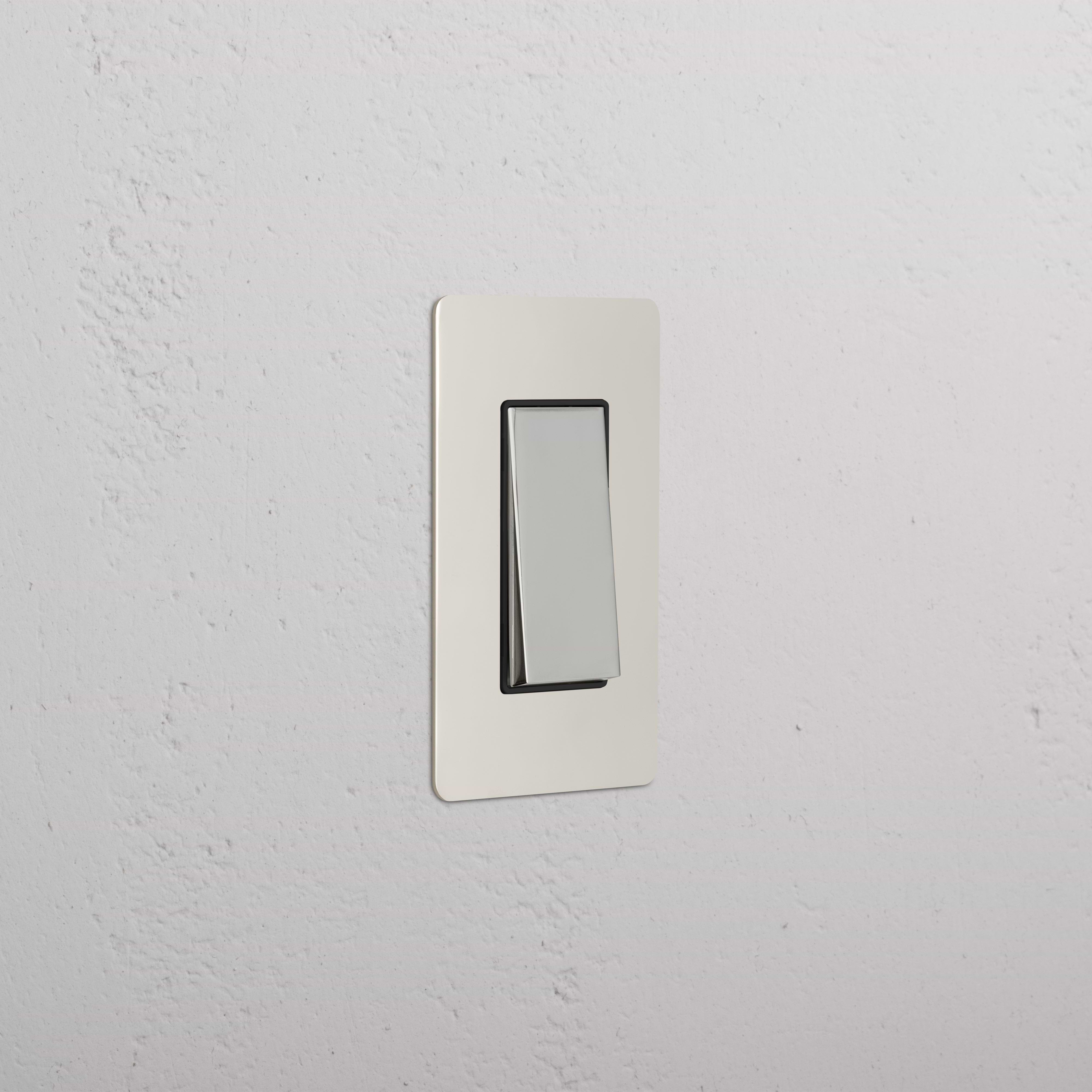 Polished nickel and black Kew 1G Retractive Rocker Switch with rectangular design on a white wall.