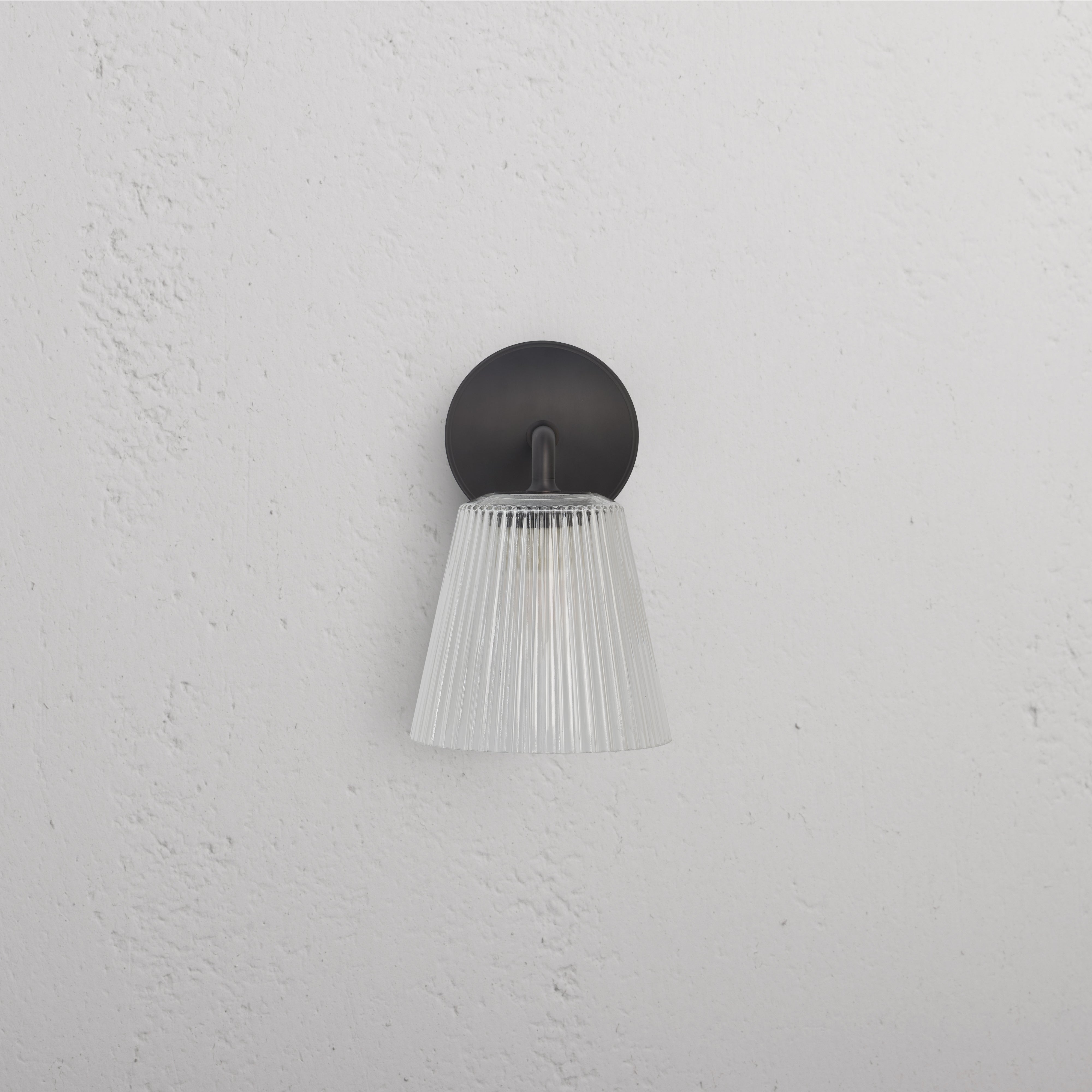 Richmond Medium Wall Light with fluted clear glass shade and bronze base, mounted on a white wall.