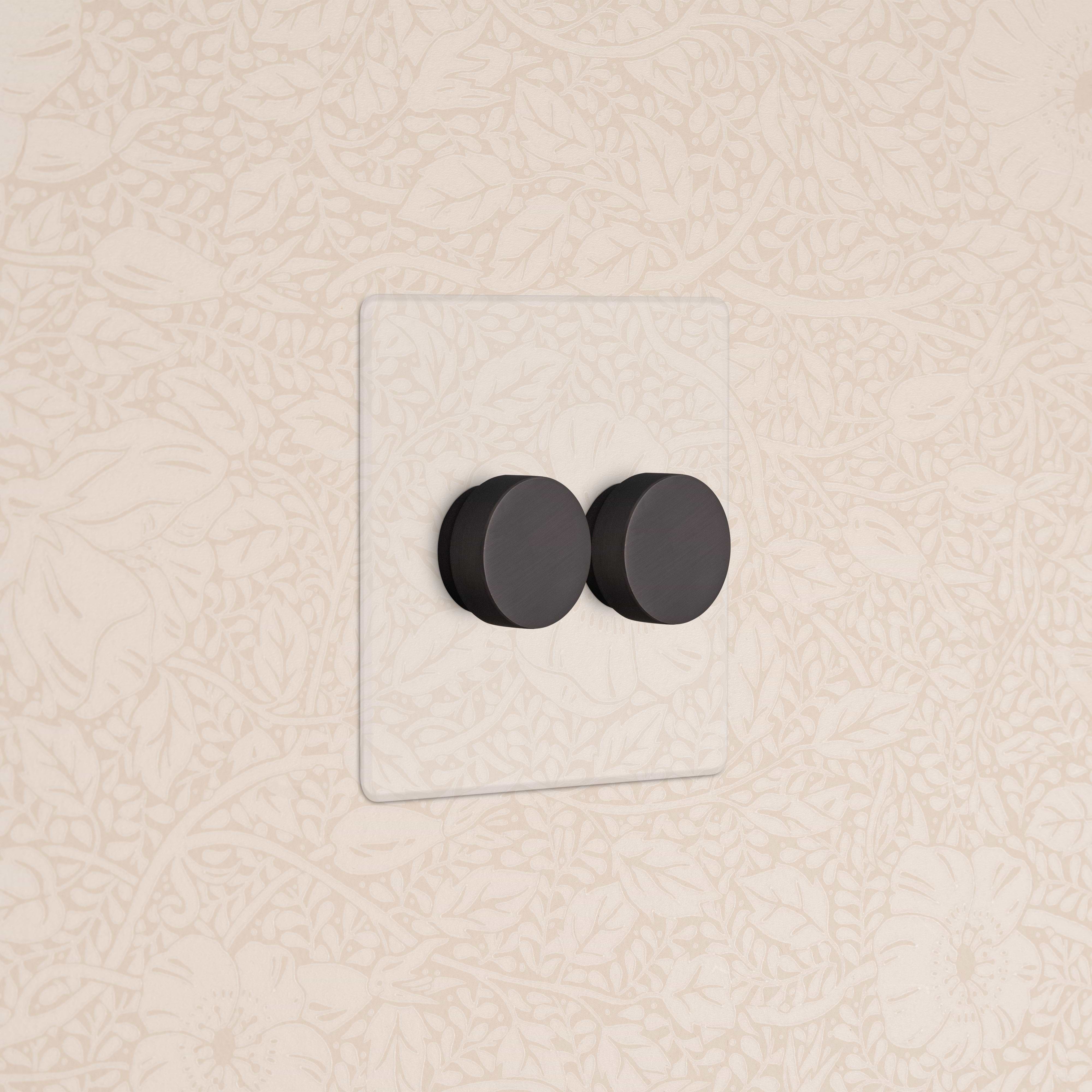 Kew 2G Dimmer Switch in clear bronze finish with two black rotary dials, mounted on a beige wall.