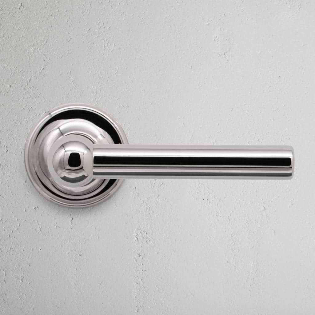 Harper Dummy Door Handle Set in polished nickel with a sleek cylindrical design, shown on a white wall.