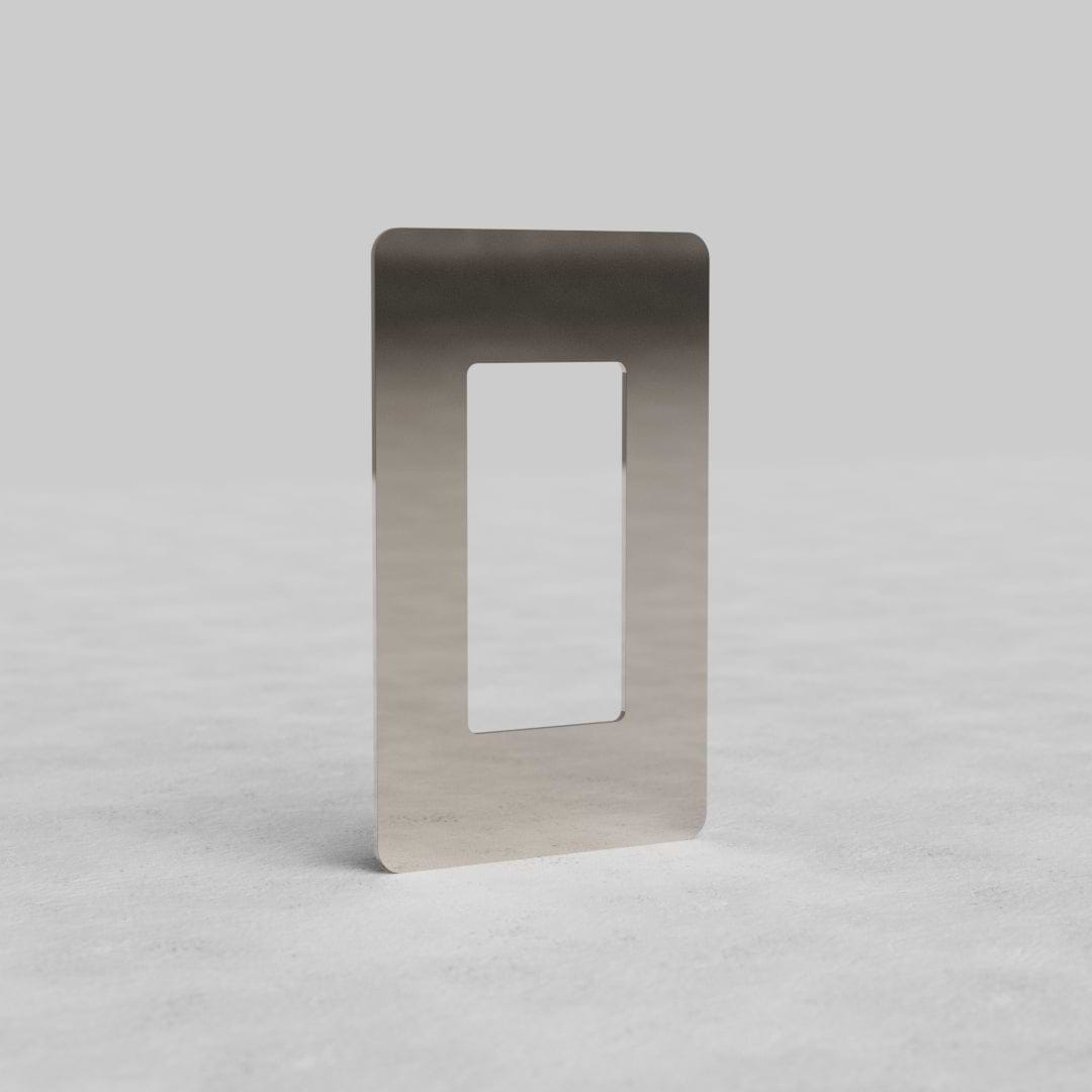 1-gang outlet plate Kew US in polished nickel, with large rectangular cutout, on light surface.