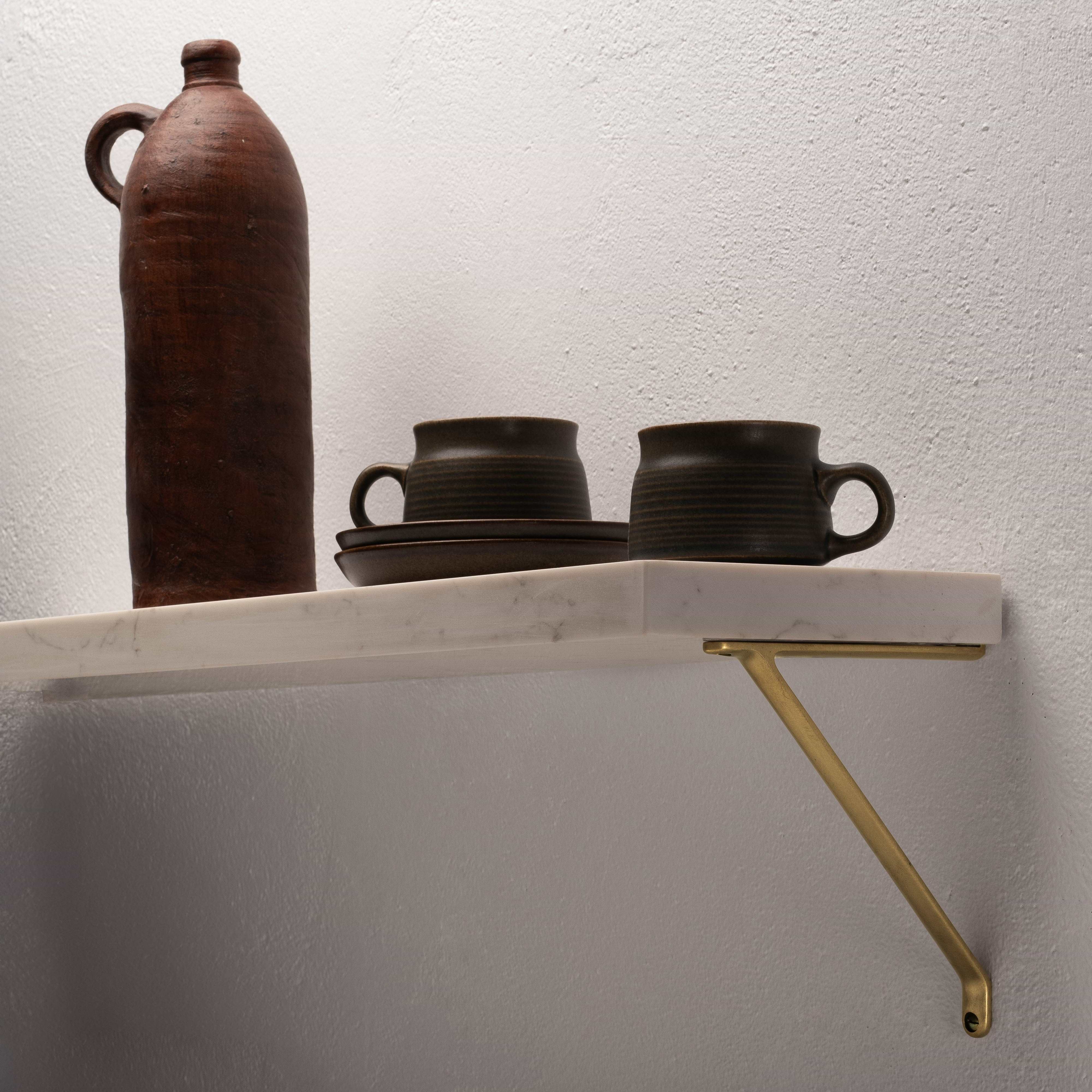 Small Brixton Shelf Bracket in Antique Brass mounted on wall, supporting a marble shelf.