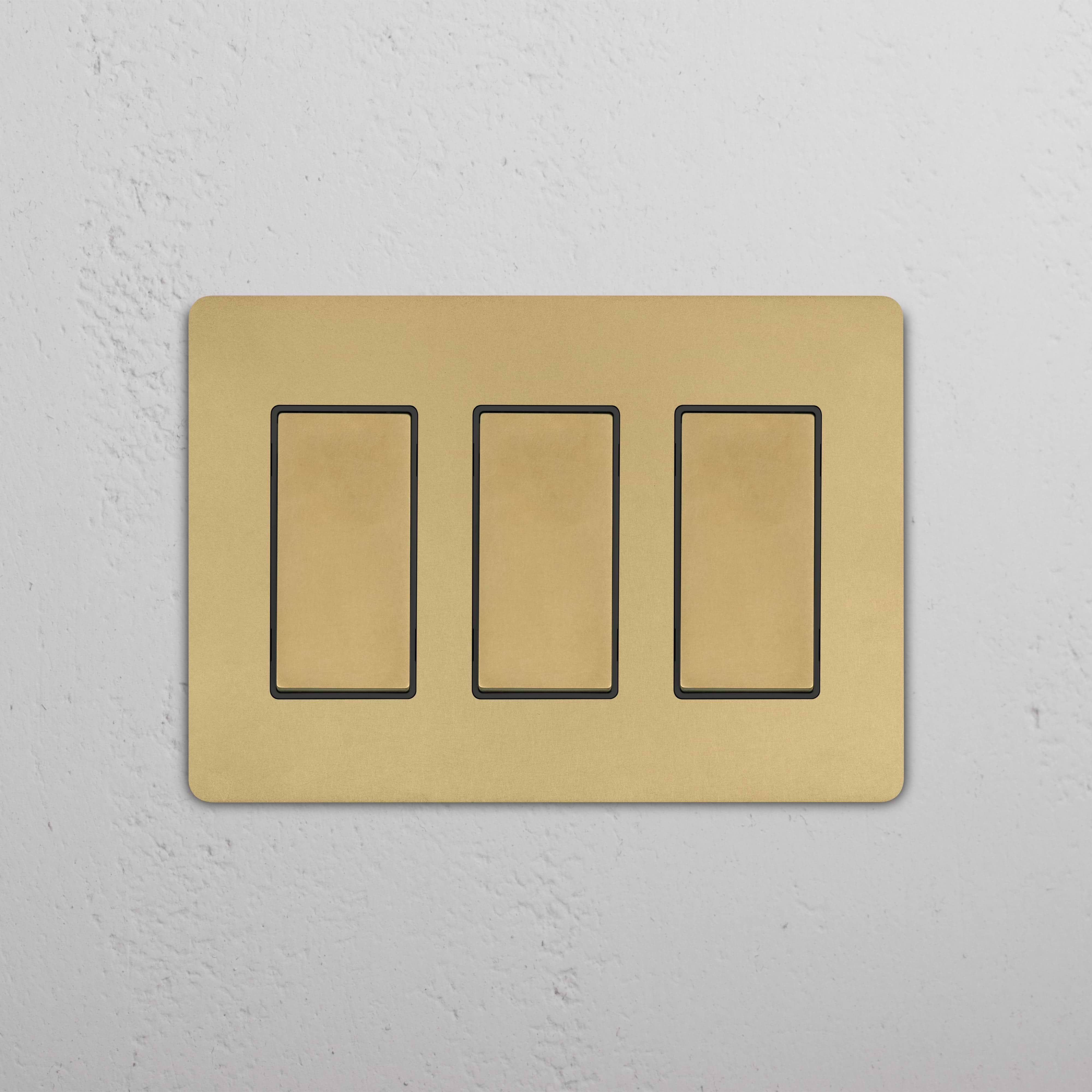 Grove 3G Rocker Switch in Antique Brass Black with three rectangular switches on a white textured wall.