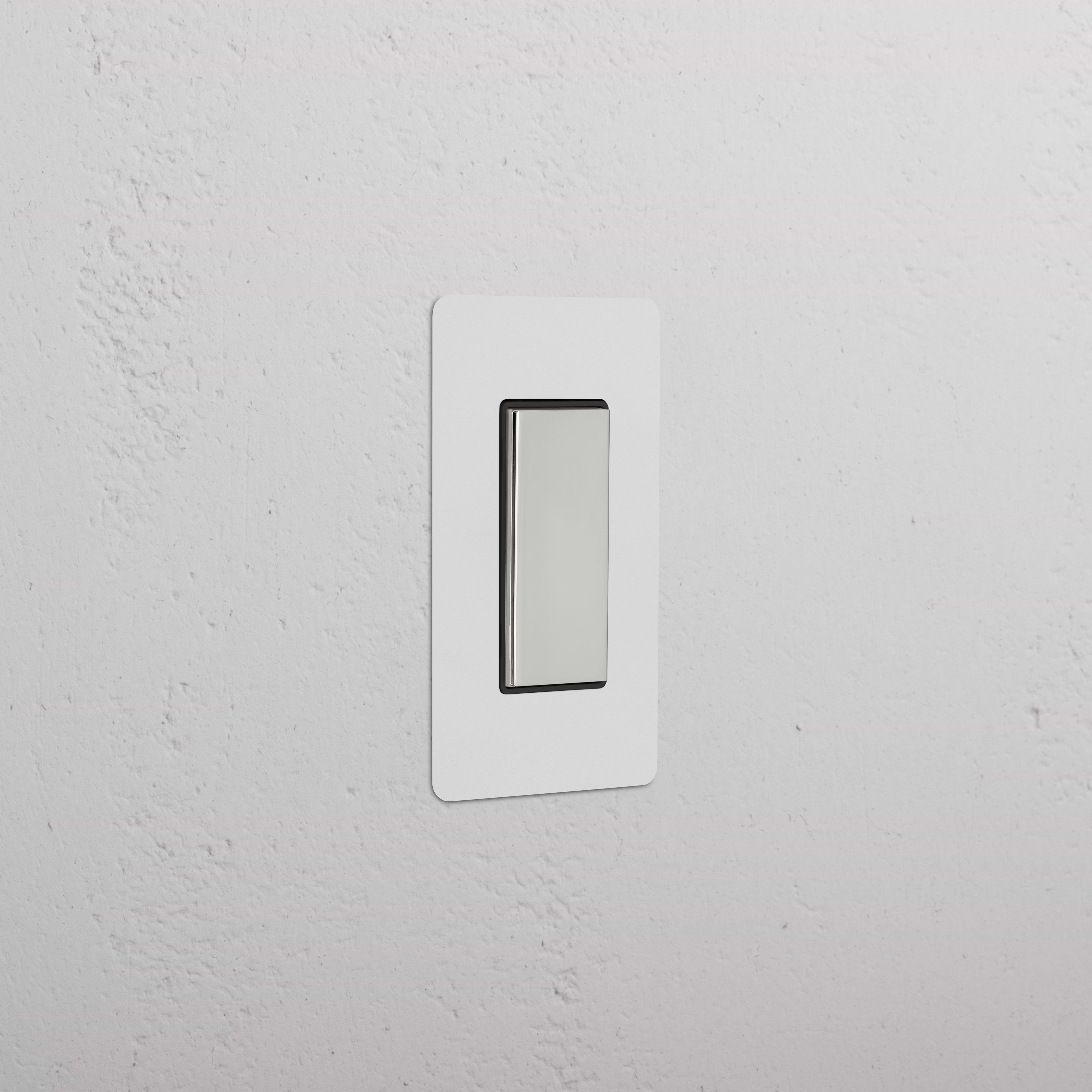 Kew 1G Center Retractive Rocker Switch in paintable polished nickel black, shown on a white wall.