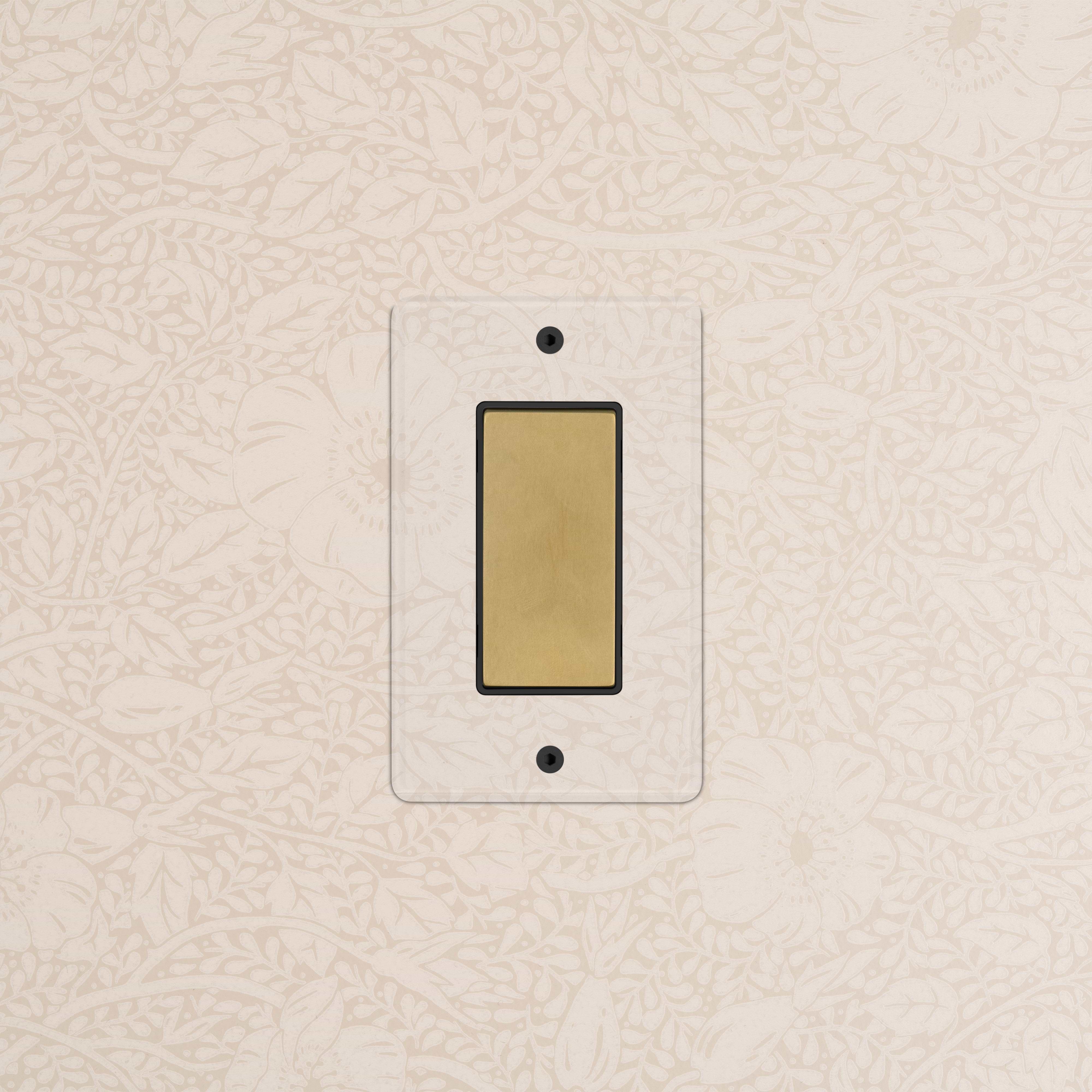 Kew 1G Center Retractive Rocker Switch in clear antique brass with black detailing, mounted on a wall.