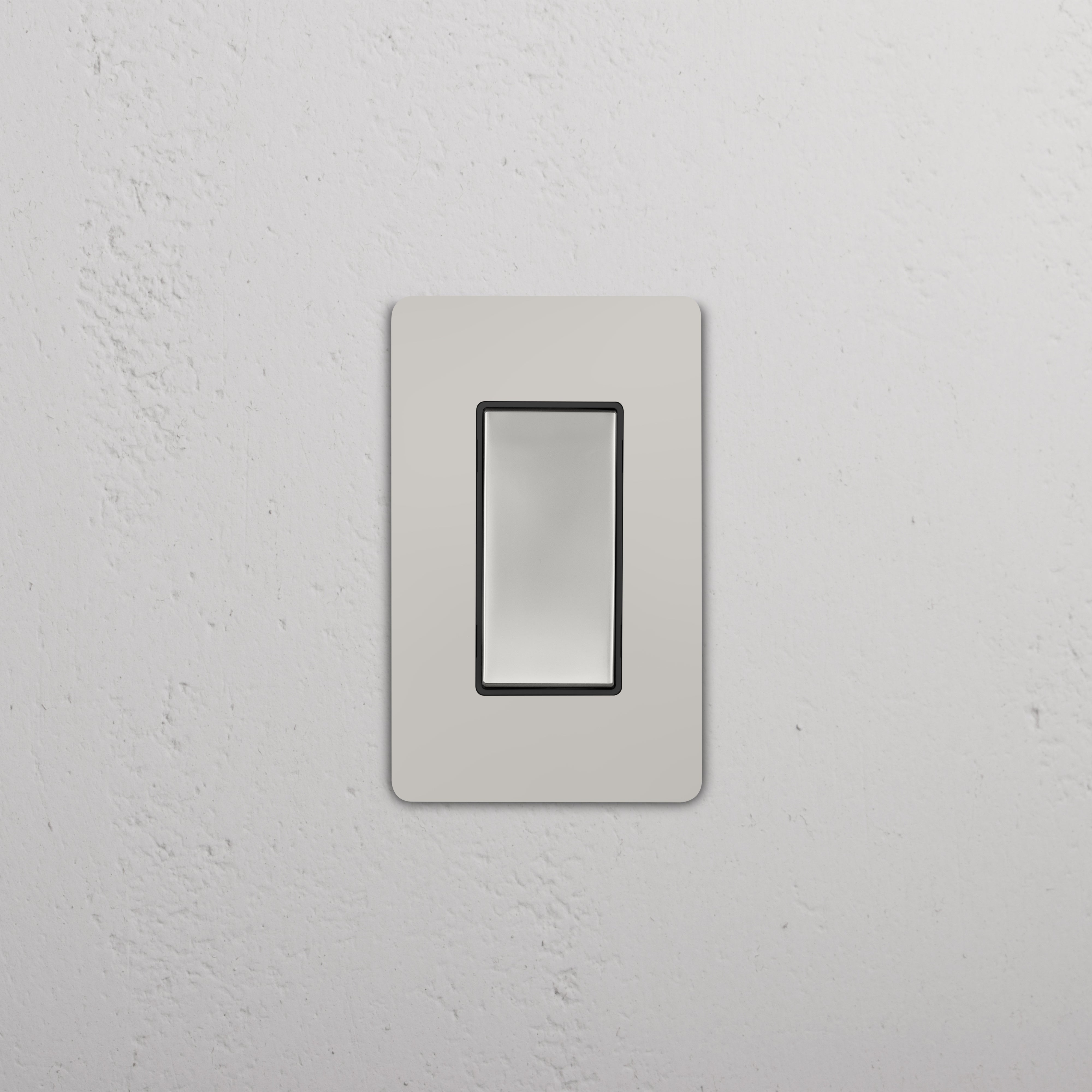 Grove 1G Rocker Switch in polished nickel with black rocker, shown installed on a white wall.