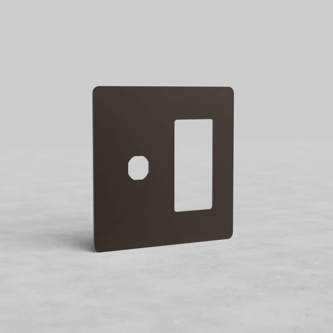 Bronze 2G switch and outlet plate (Kew US) with one switch and one outlet opening, on a light surface.