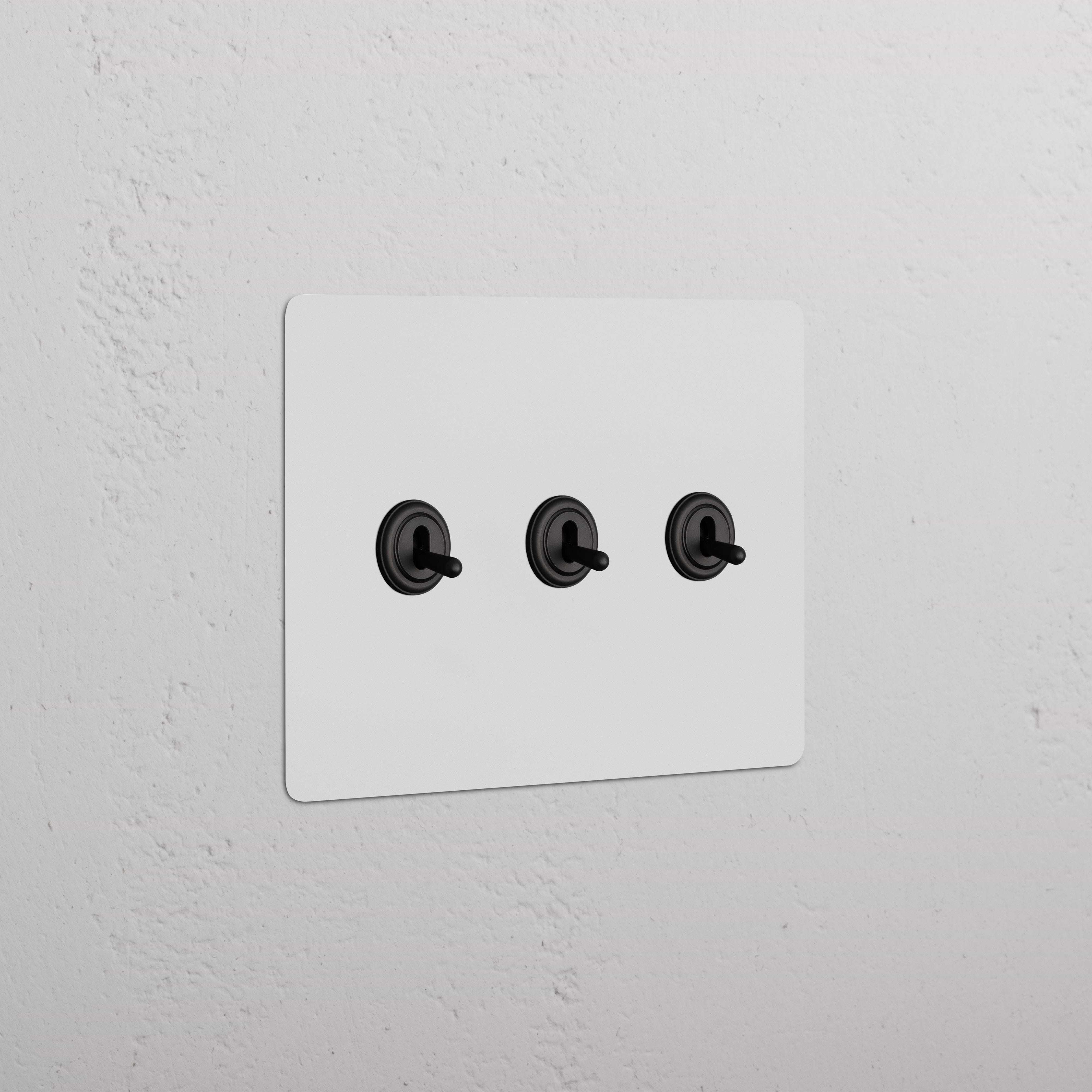Kew 3G Toggle Switch in paintable bronze finish, featuring three black toggles on a rectangular wall plate.