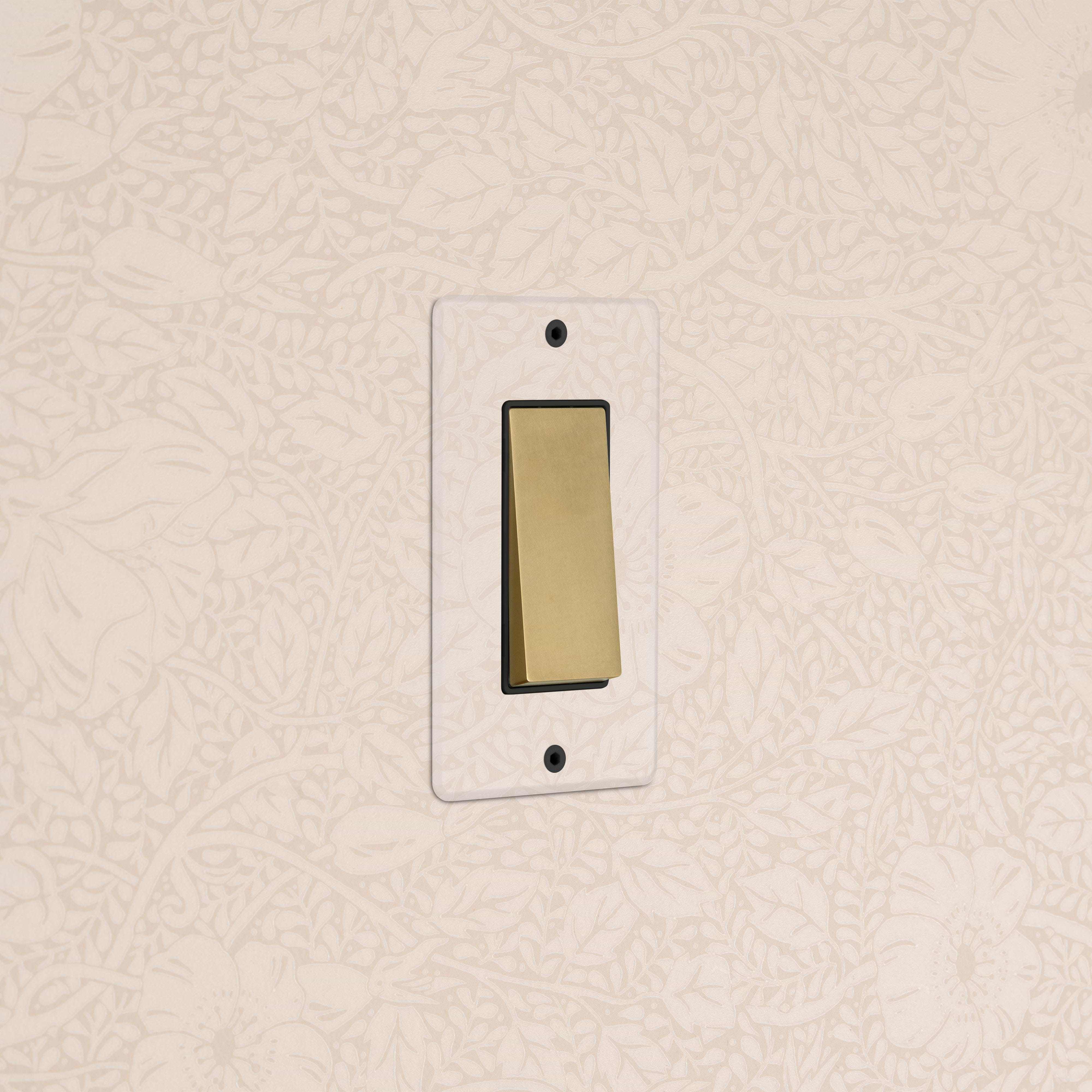 Kew 1G Four Way Rocker Switch in clear antique brass with black rockers, mounted on a wall.