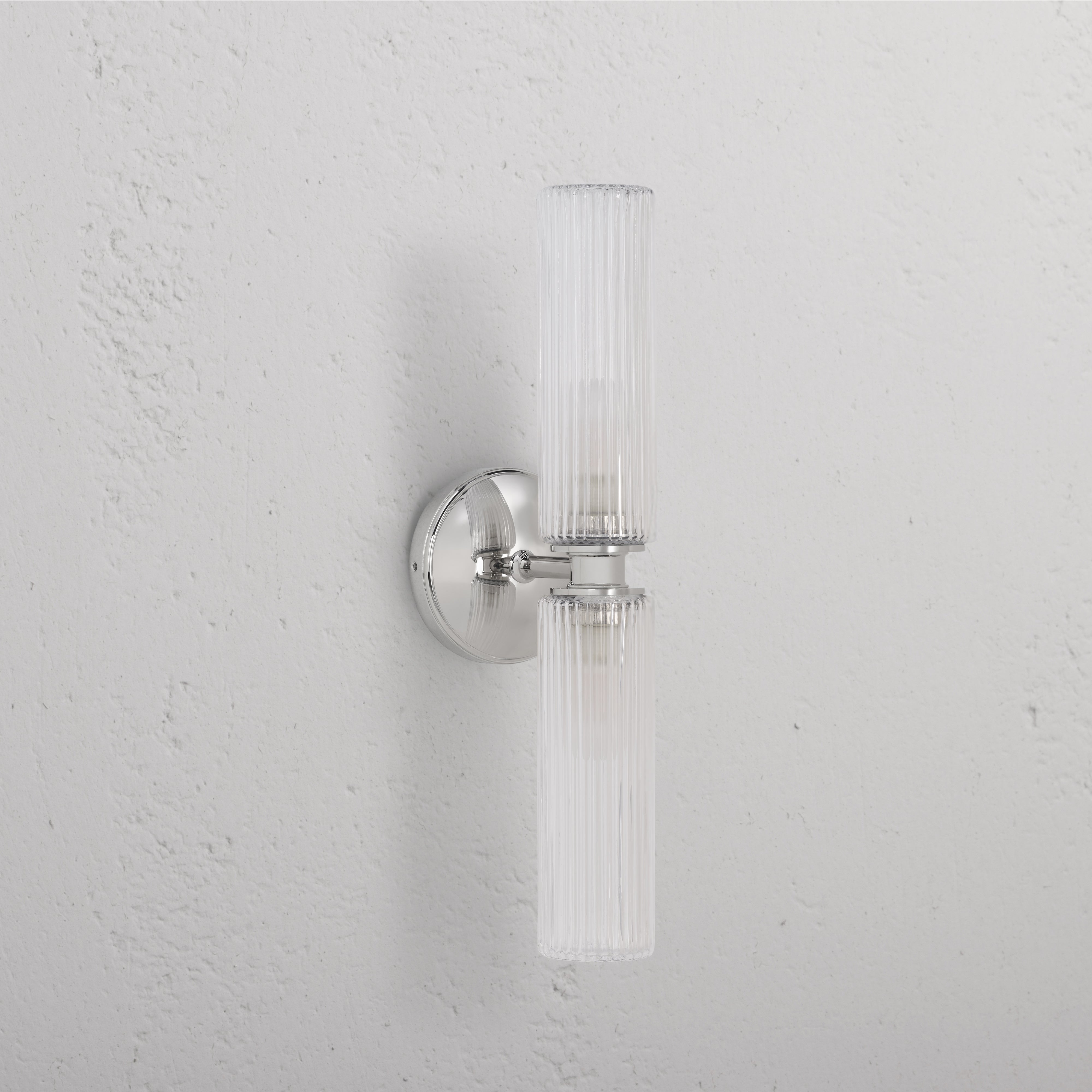 Claremont Medium Wall Light with fluted glass shade and polished nickel base, mounted on a white wall.
