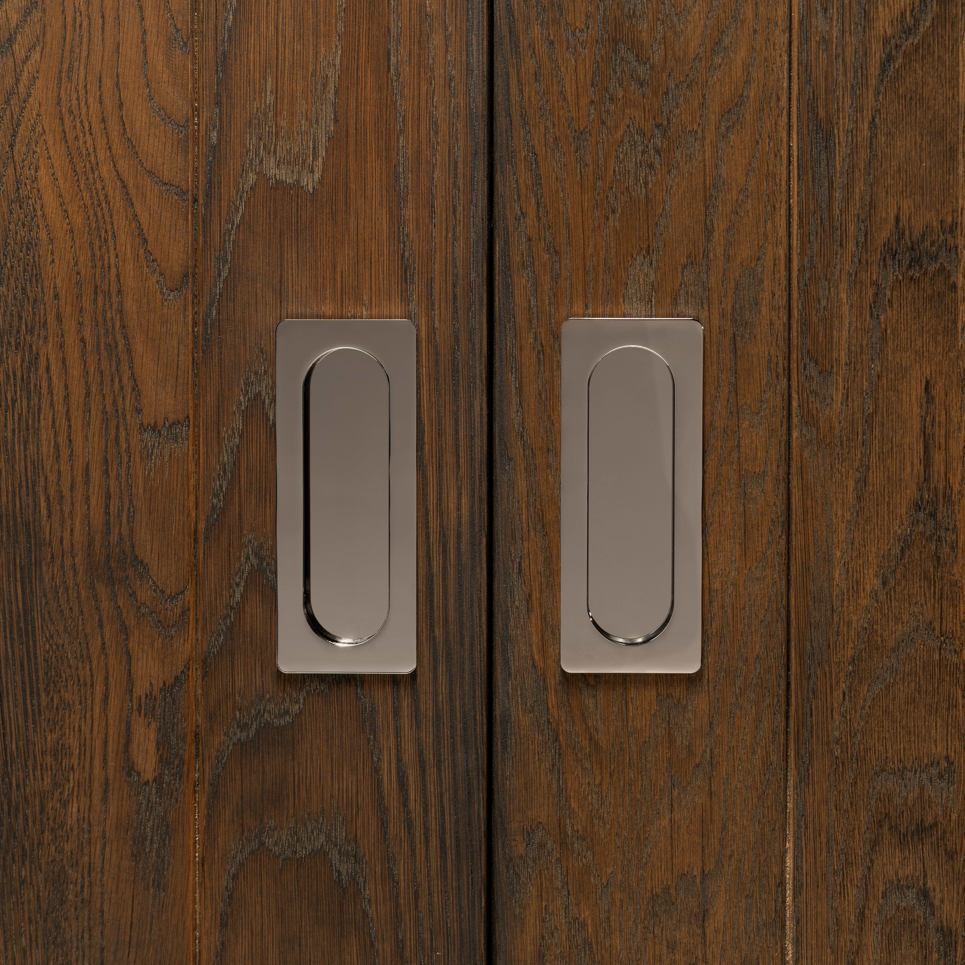 Regent Recessed Medium Pull in polished nickel installed on dark wood sliding doors, showing visible grain.