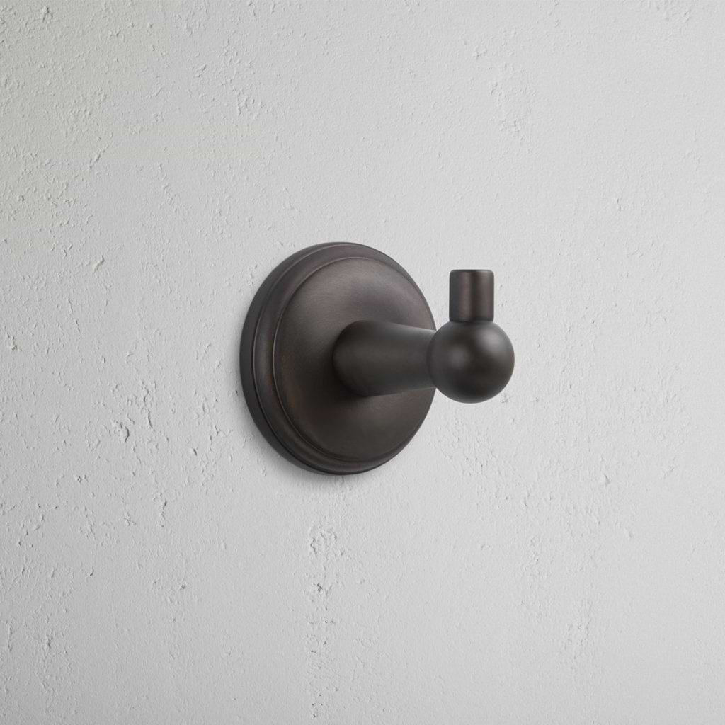 Hyde Hook in dark bronze finish with rounded design and circular base, mounted on a white wall.