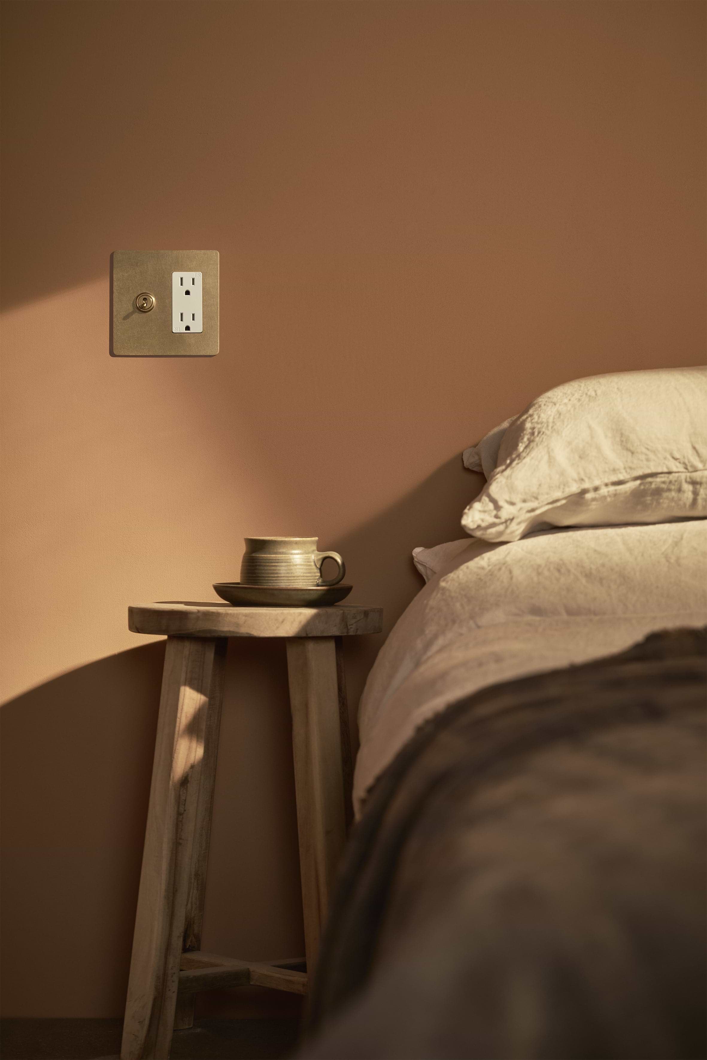 Kew 2G Toggle Switch & Outlet in Antique Brass White finish, mounted on a wall.