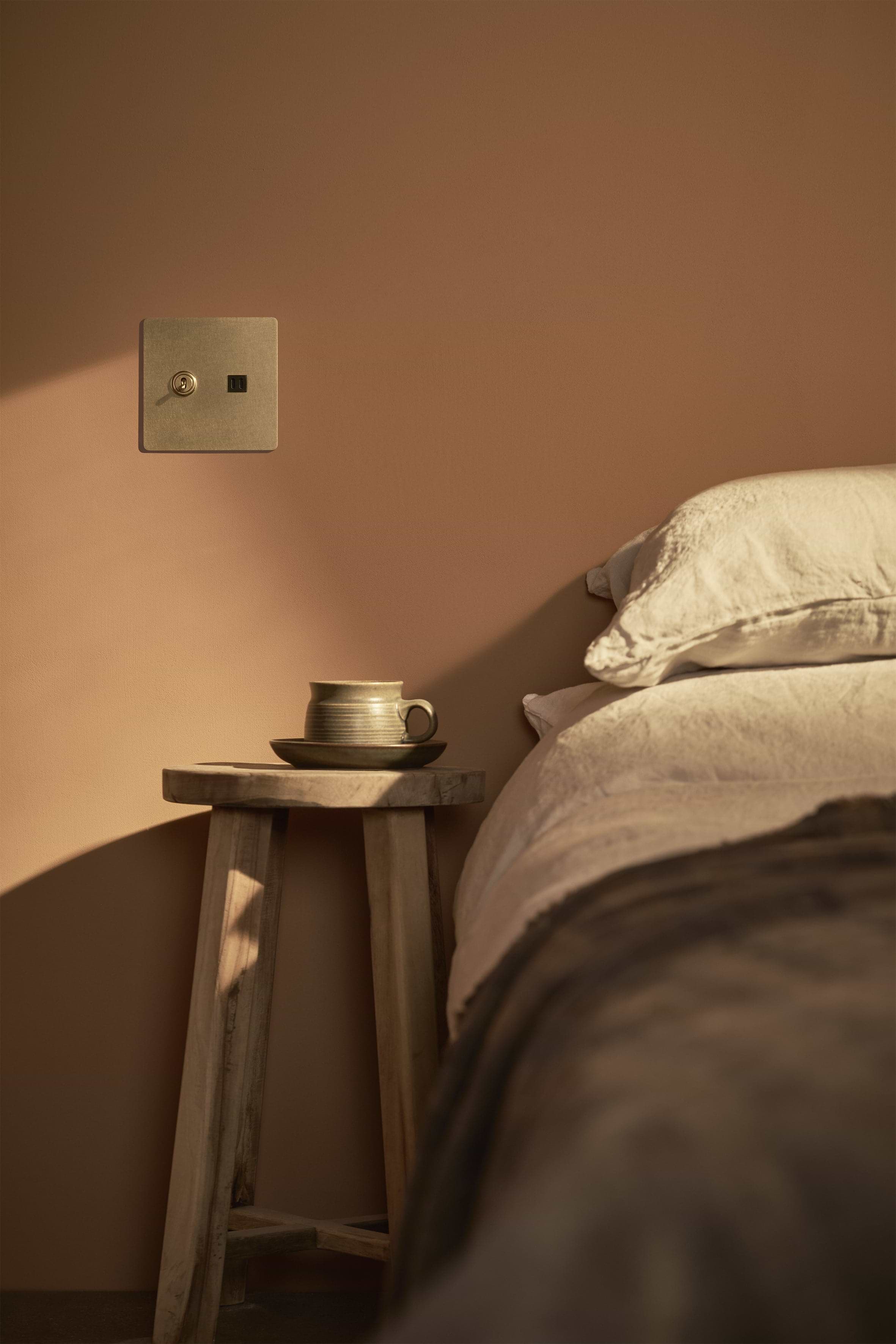 Kew 2G Toggle Switch & Fast Charge USB in antique brass black finish, mounted on a beige wall.