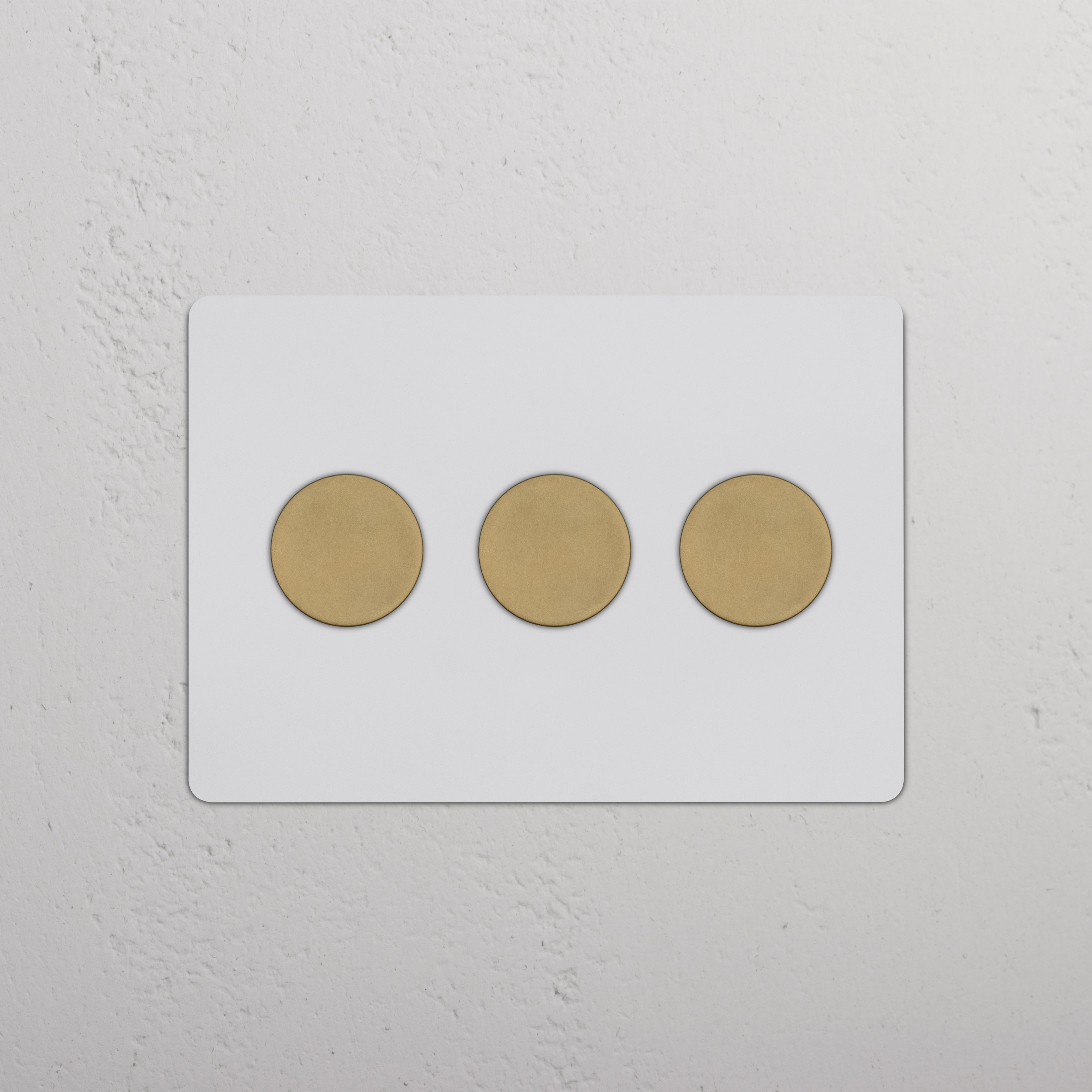 Kew 3G Dimmer Switch in paintable antique brass finish with three round knobs on a white wall.