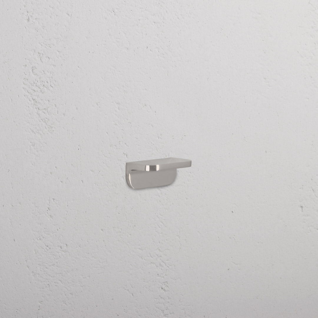 Oxford Furniture Handle Extra Small in polished nickel, mounted on a textured white wall.