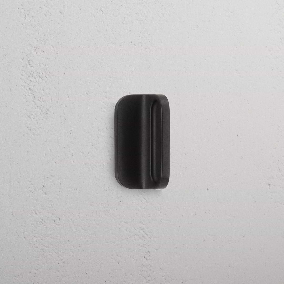 Bronze Oxford Furniture Handle Extra Small with a smooth, rounded rectangular design, shown against a white wall.