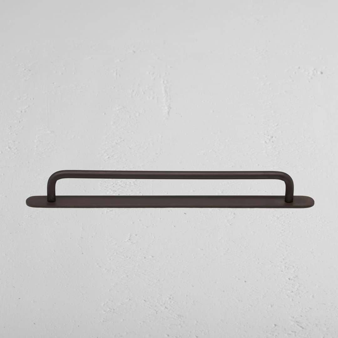 Medium-sized Kilburn Furniture Handle in bronze finish, mounted horizontally on a white wall.