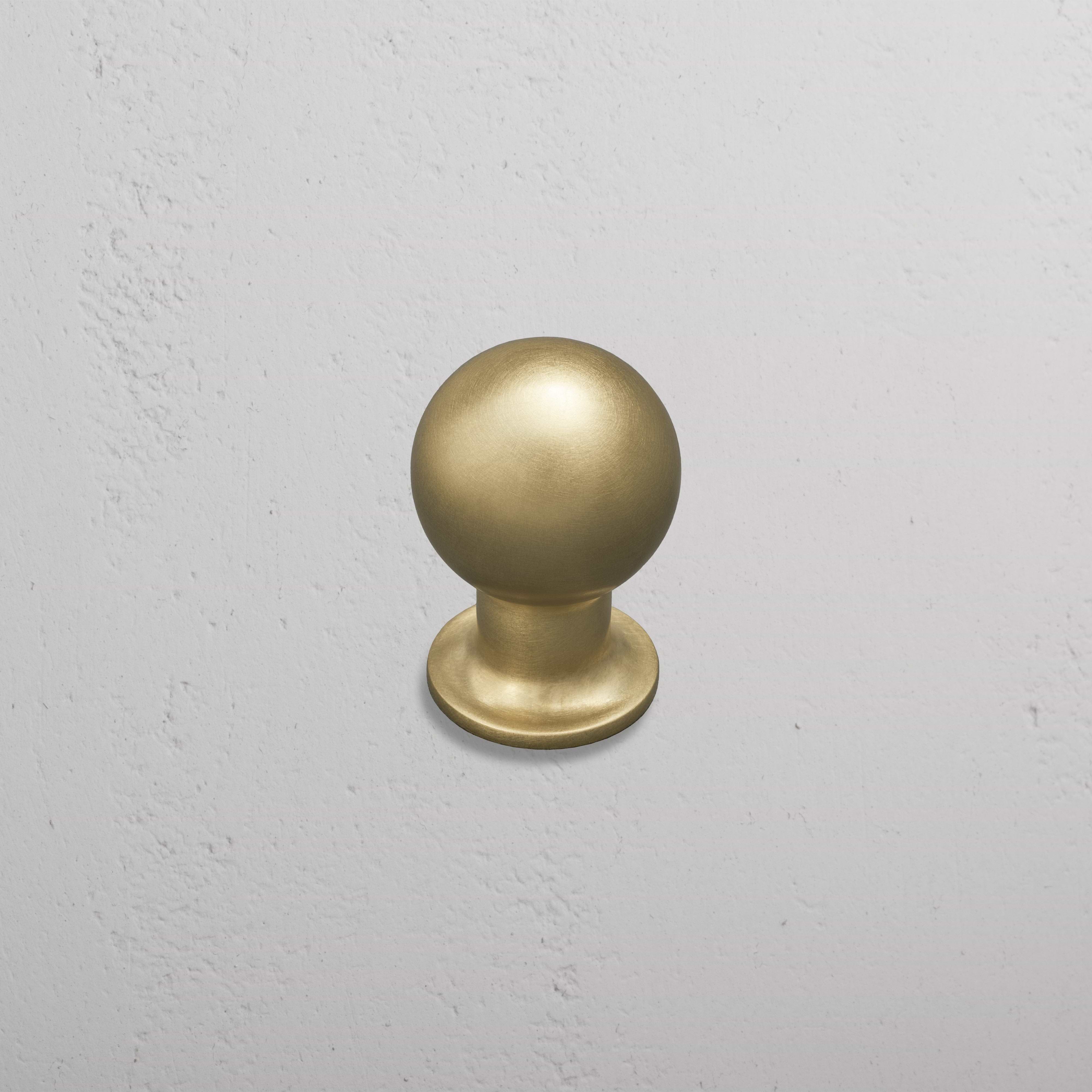 Bayswater Furniture Knob Medium in antique brass finish, installed on a light gray textured wall.