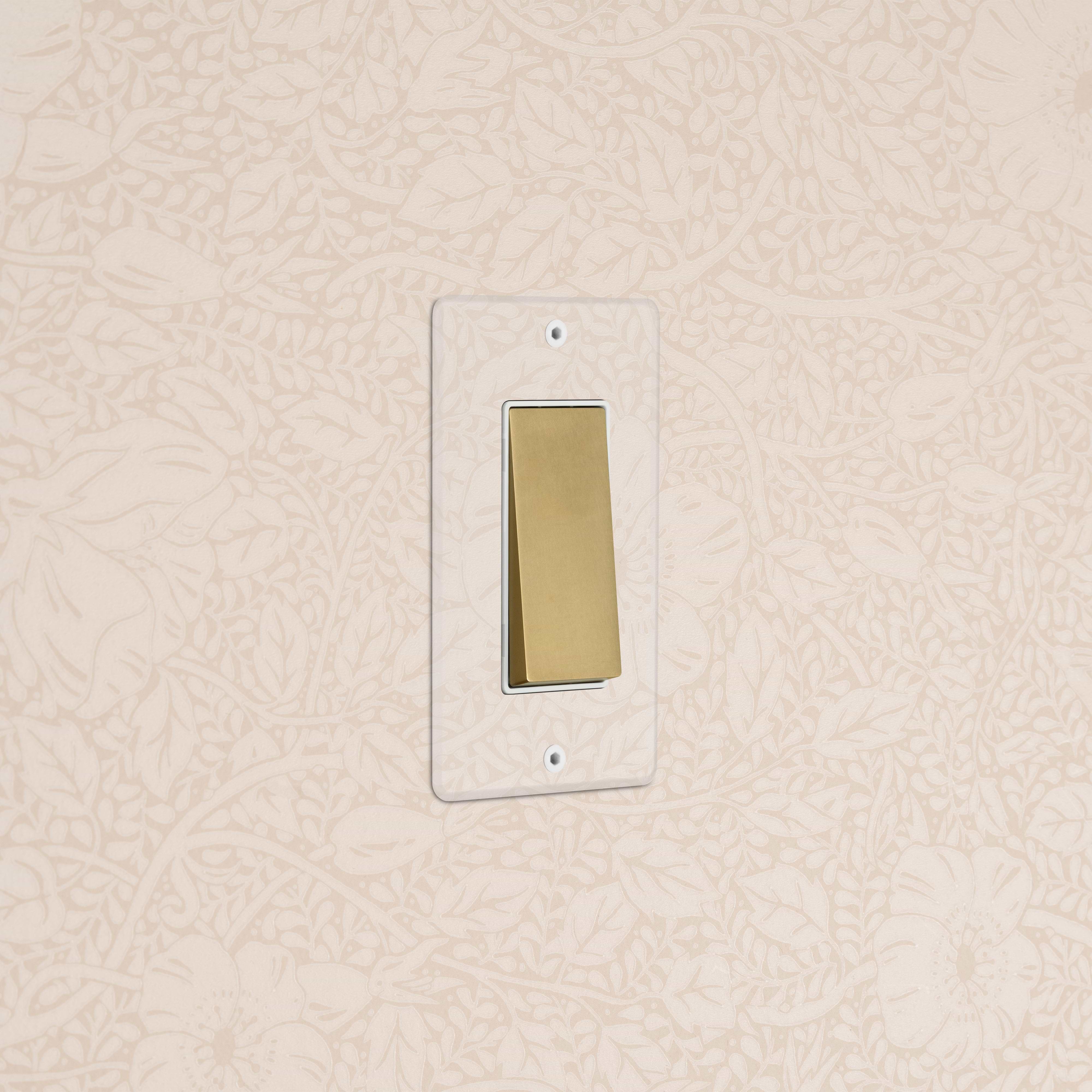 Kew 1G Rocker Switch in Clear Antique Brass with a white plate, shown installed on a wall.