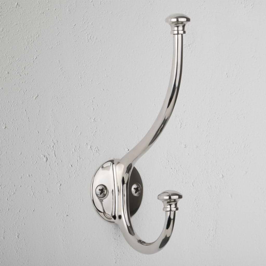 Polished Nickel Mews Hook with two curved prongs mounted on a textured white wall.