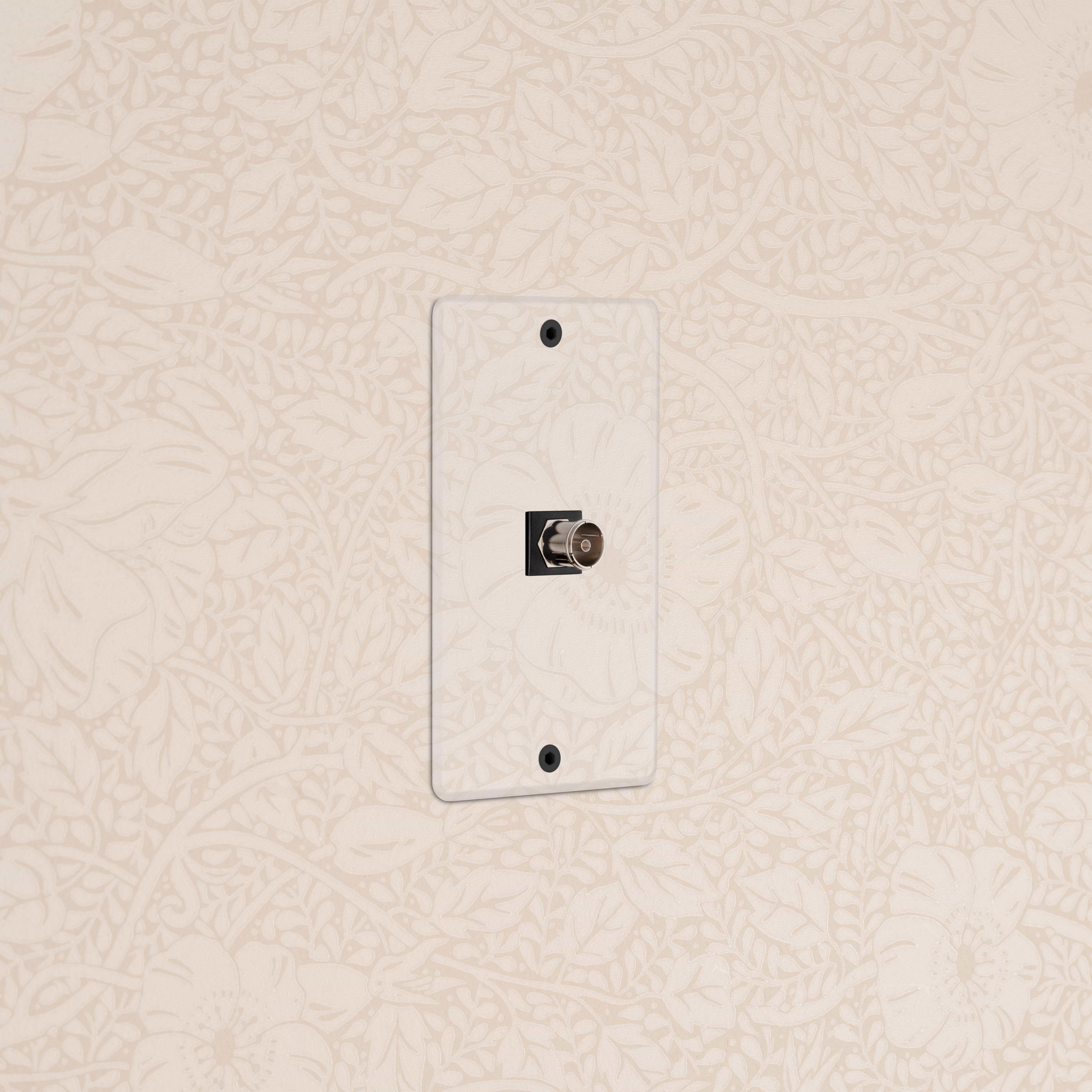 Kew 1G TV Keystone - Clear Black wall plate for coaxial TV cable connection, shown on a beige wall.