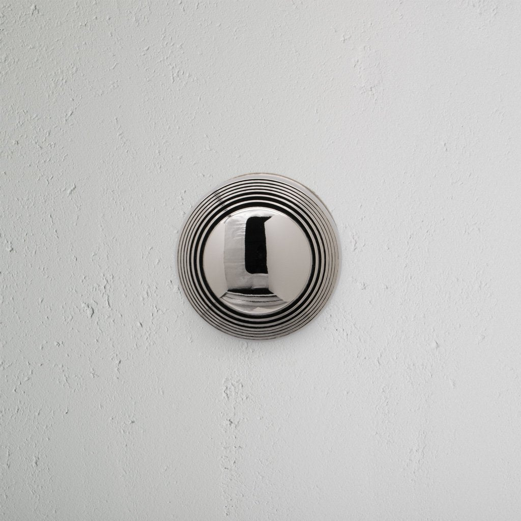 Poplar Dummy Door Knob Set in polished nickel with circular ridges, mounted on a white textured wall.