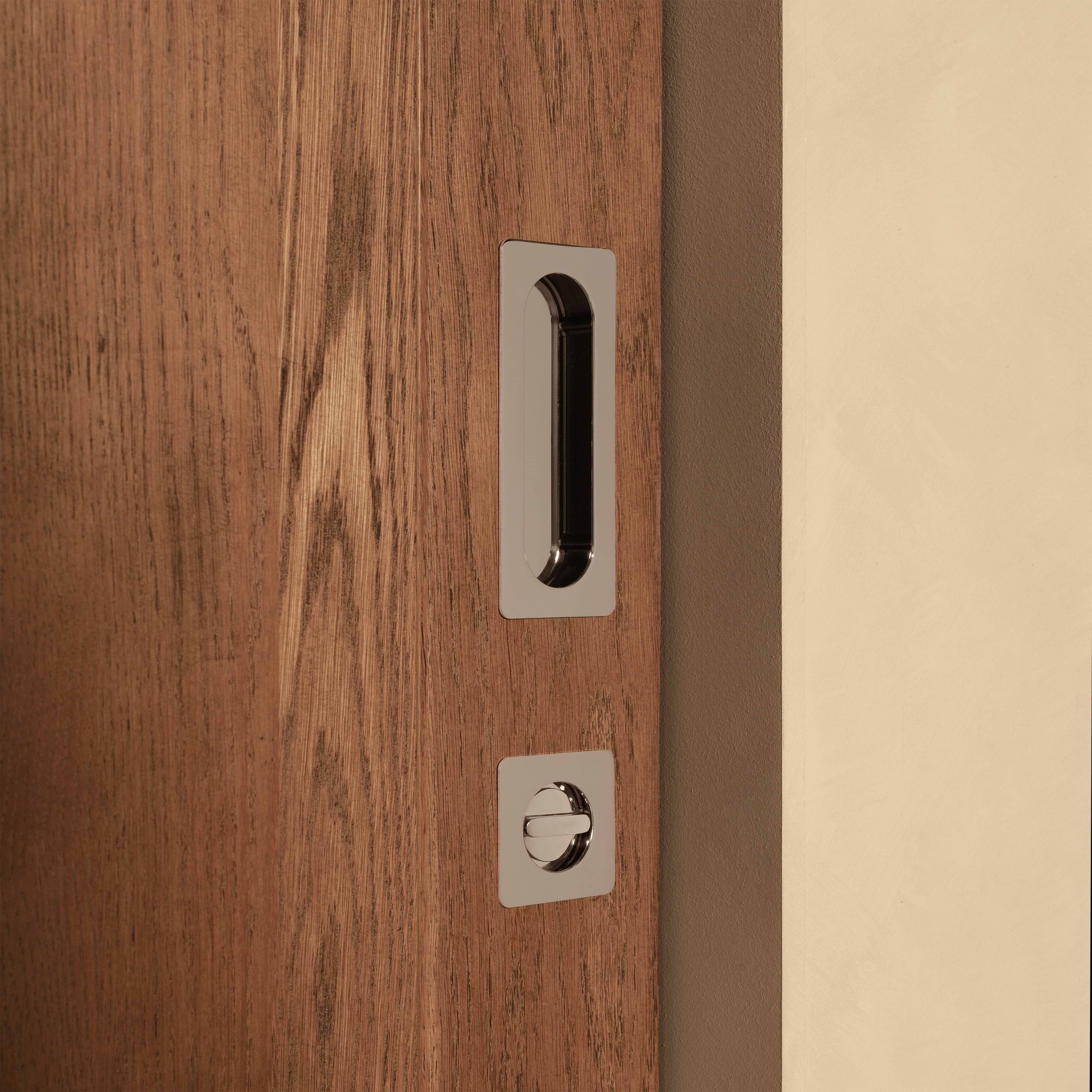 Regent Recessed Medium Pull in Polished Nickel installed on a wooden sliding door with a square lock plate.