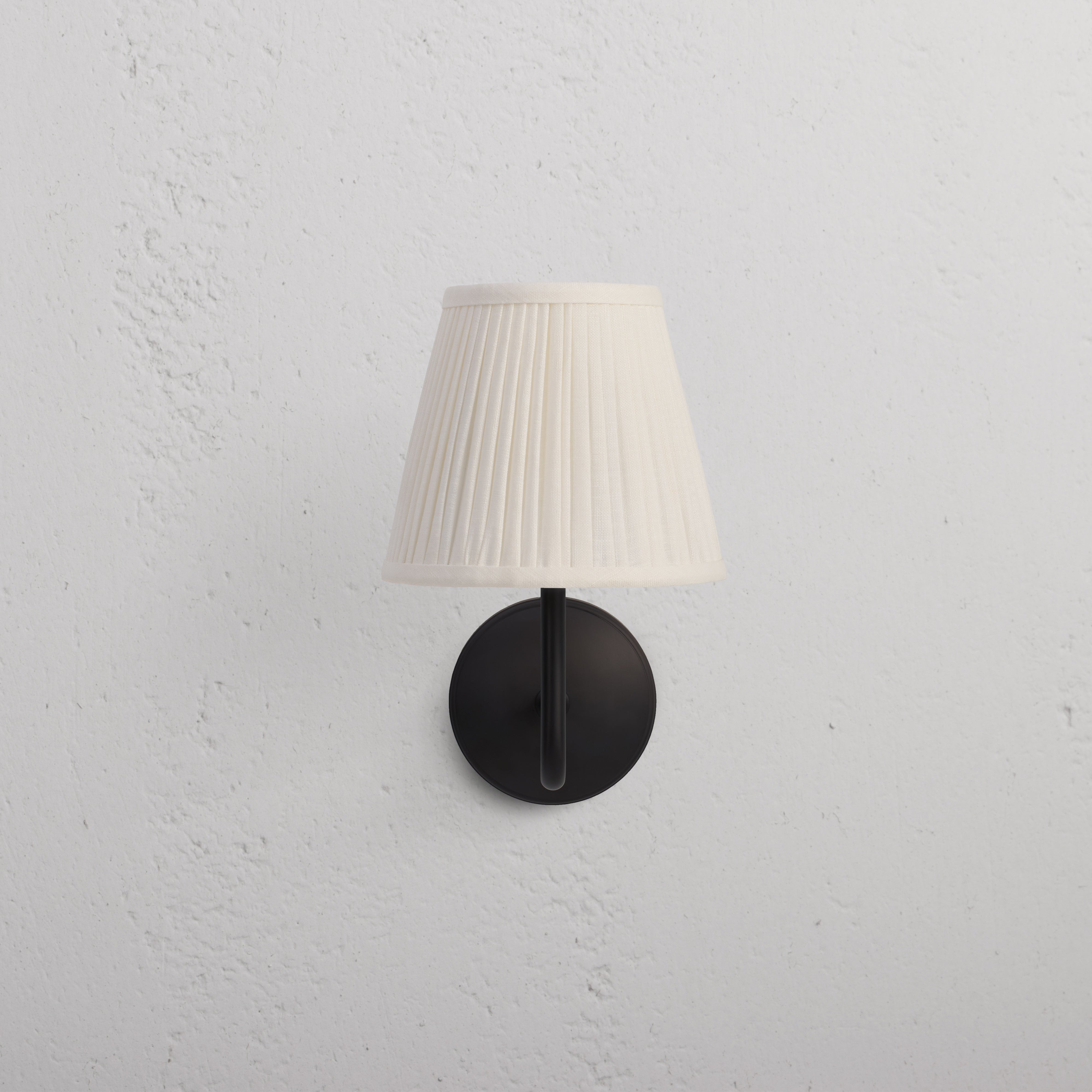 Malvern Medium Wall Light Alabaster White in bronze finish with pleated white shade mounted on wall.