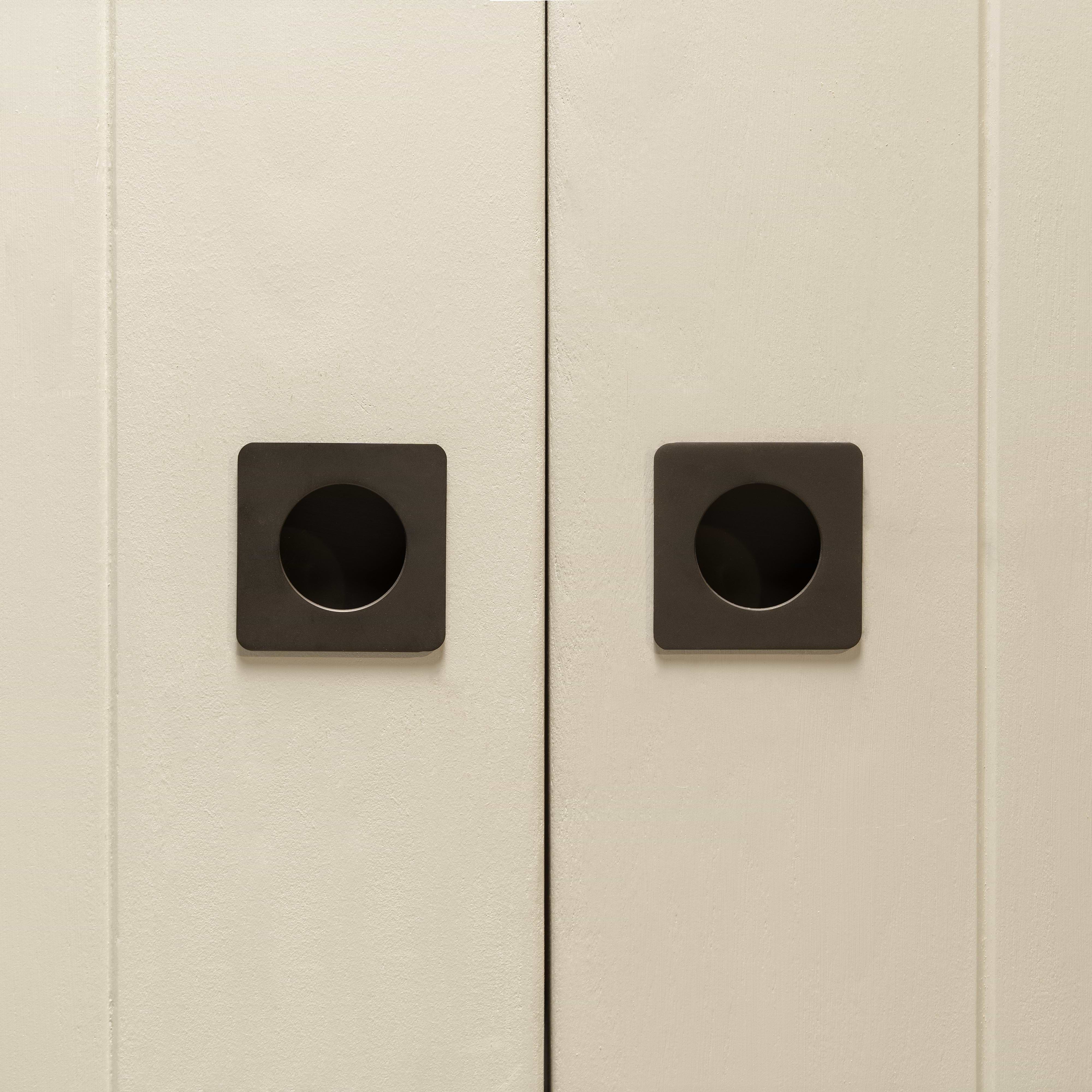 Close-up of two cabinet doors with Regent Recessed Small Pulls in bronze, showing their square, minimalist design.