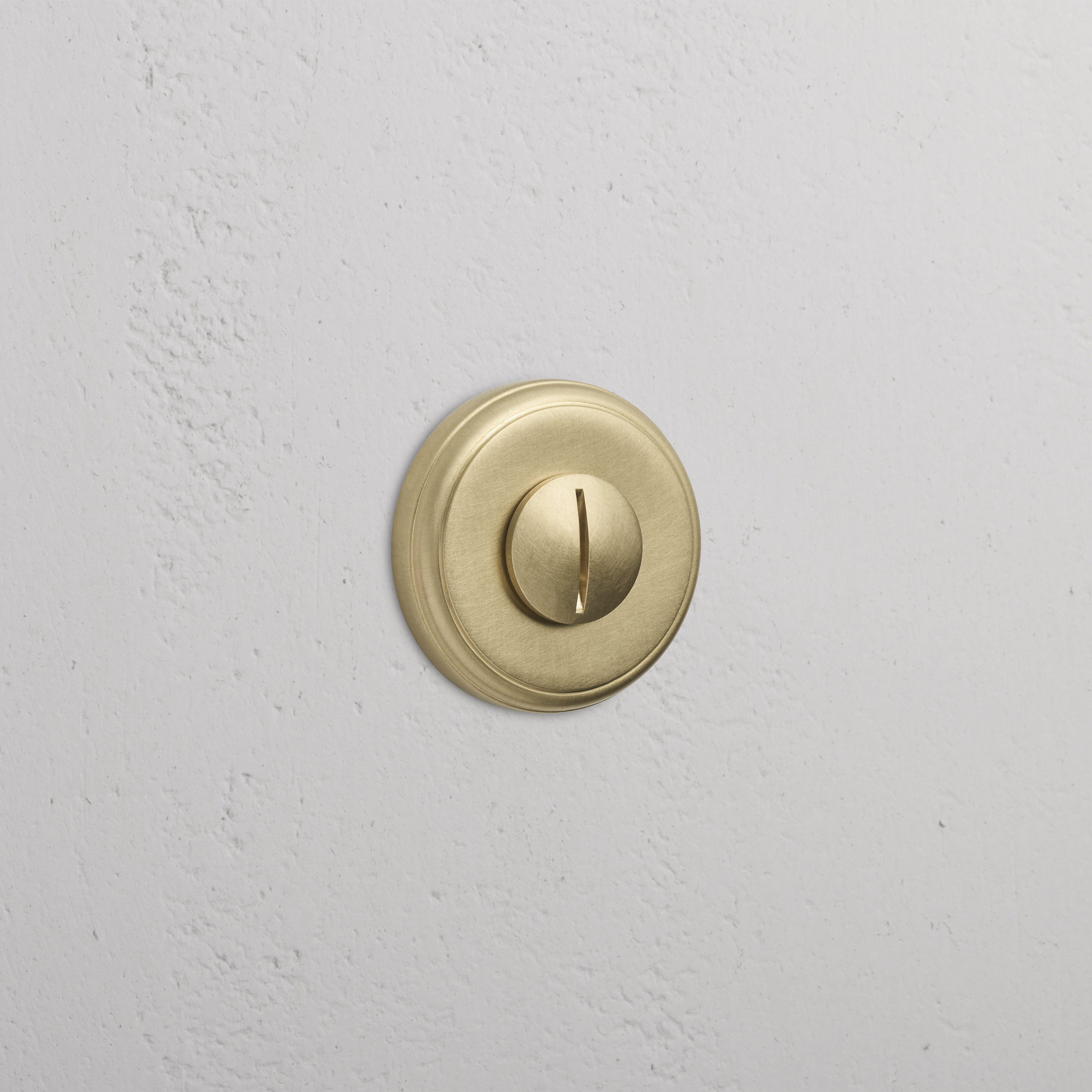 Canning Privacy Deadbolt in Antique Brass with a round turn knob, mounted on a white textured wall.