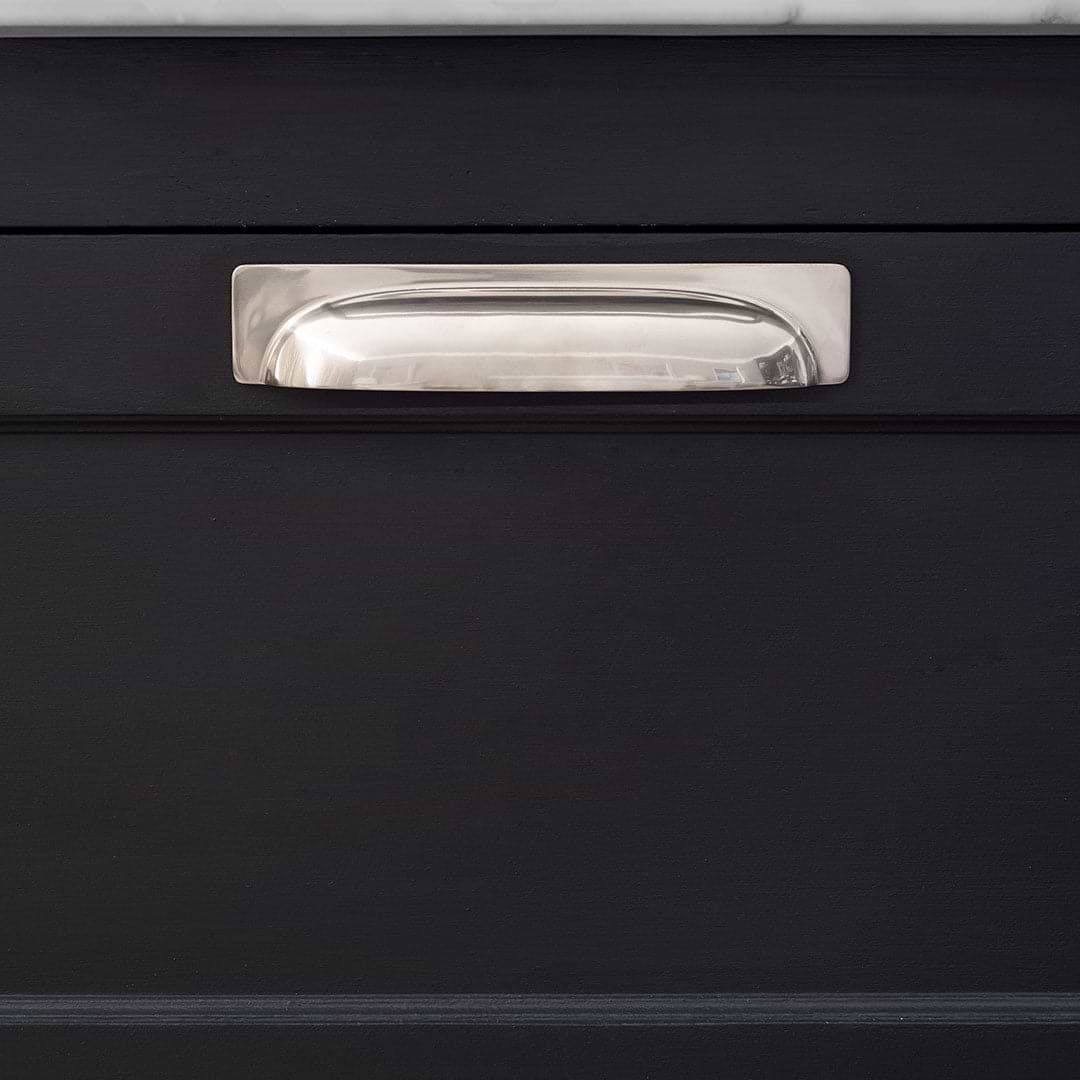 Medium-sized Elm Cup Handle in polished nickel finish, mounted on a matte black cabinet drawer.