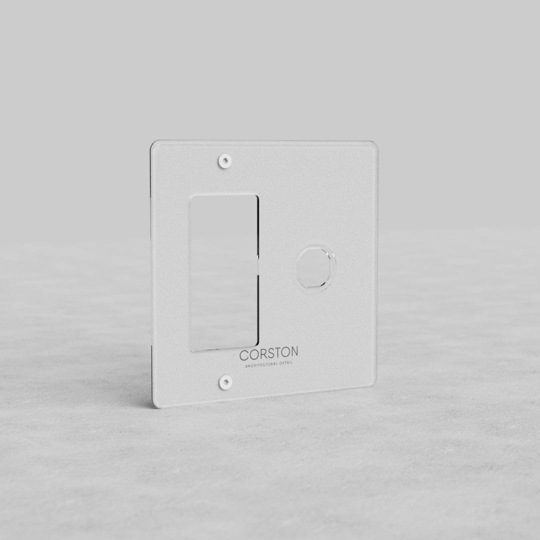 Clear 2G switch and outlet plate (Kew US) with one rectangular and one circular cutout, 'CORSTON' label.