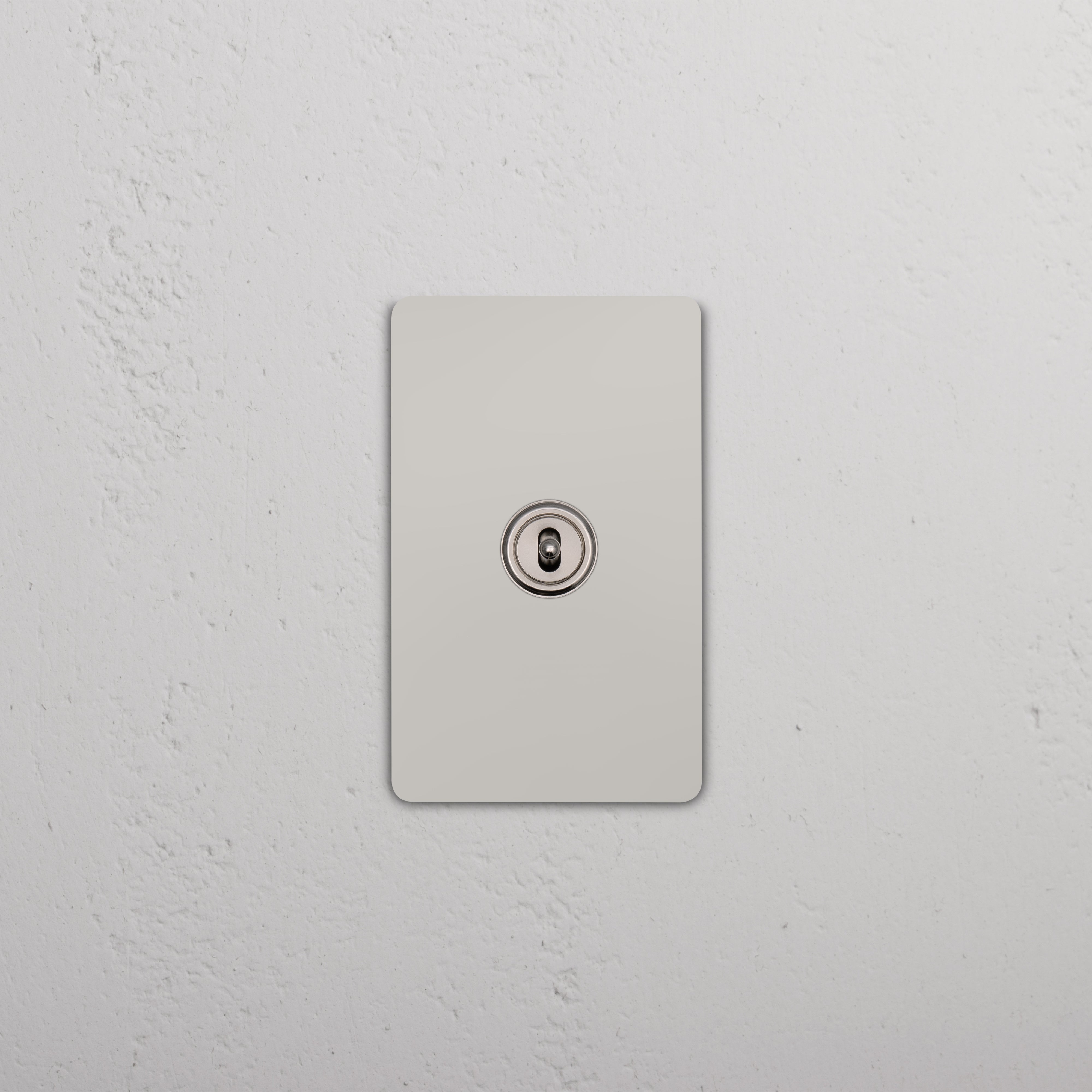 Grove 1G Center Retractive Toggle Switch in polished nickel, mounted on a white textured wall.