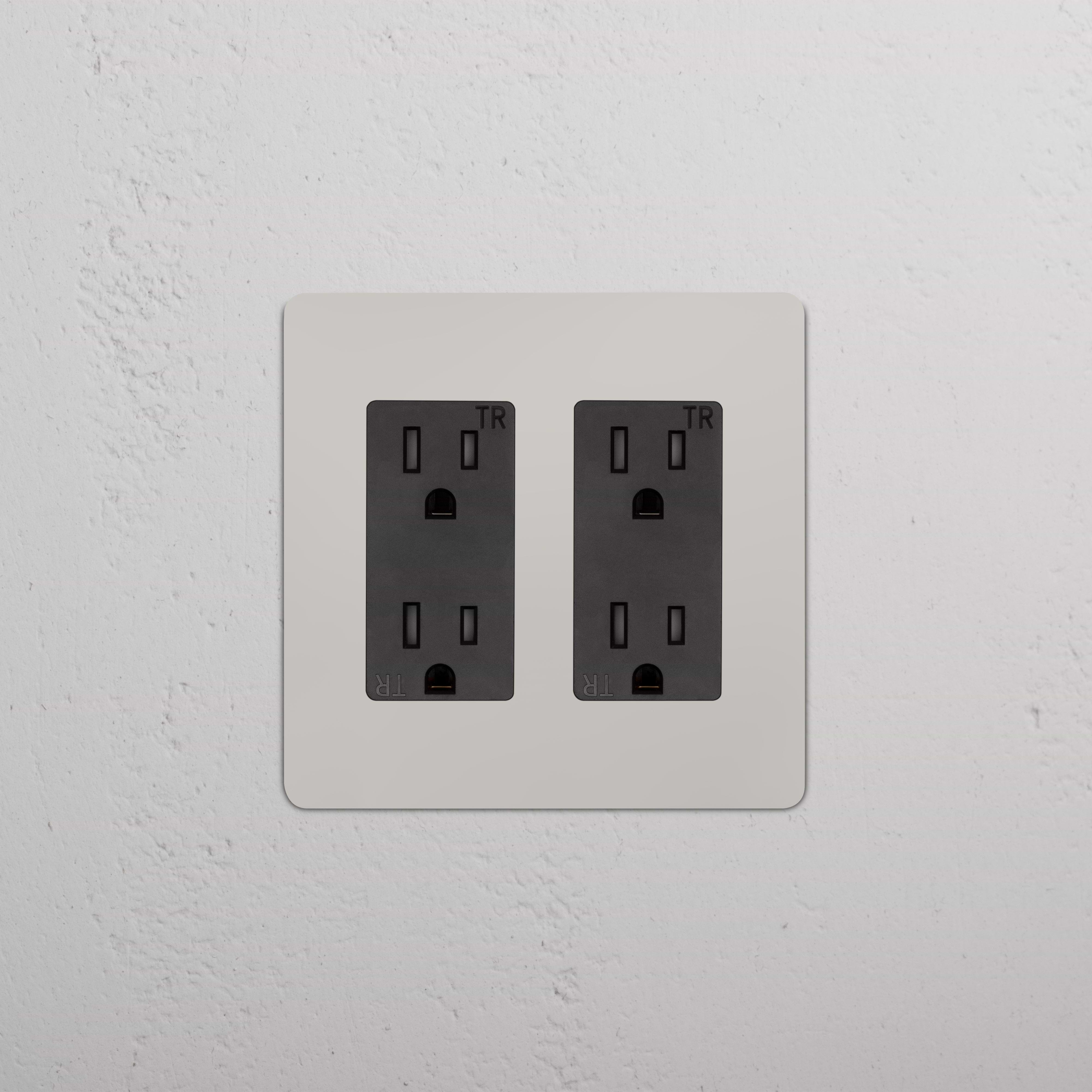 Kew 2G Outlet in polished nickel with black two-gang sockets, wall-mounted on a textured surface.