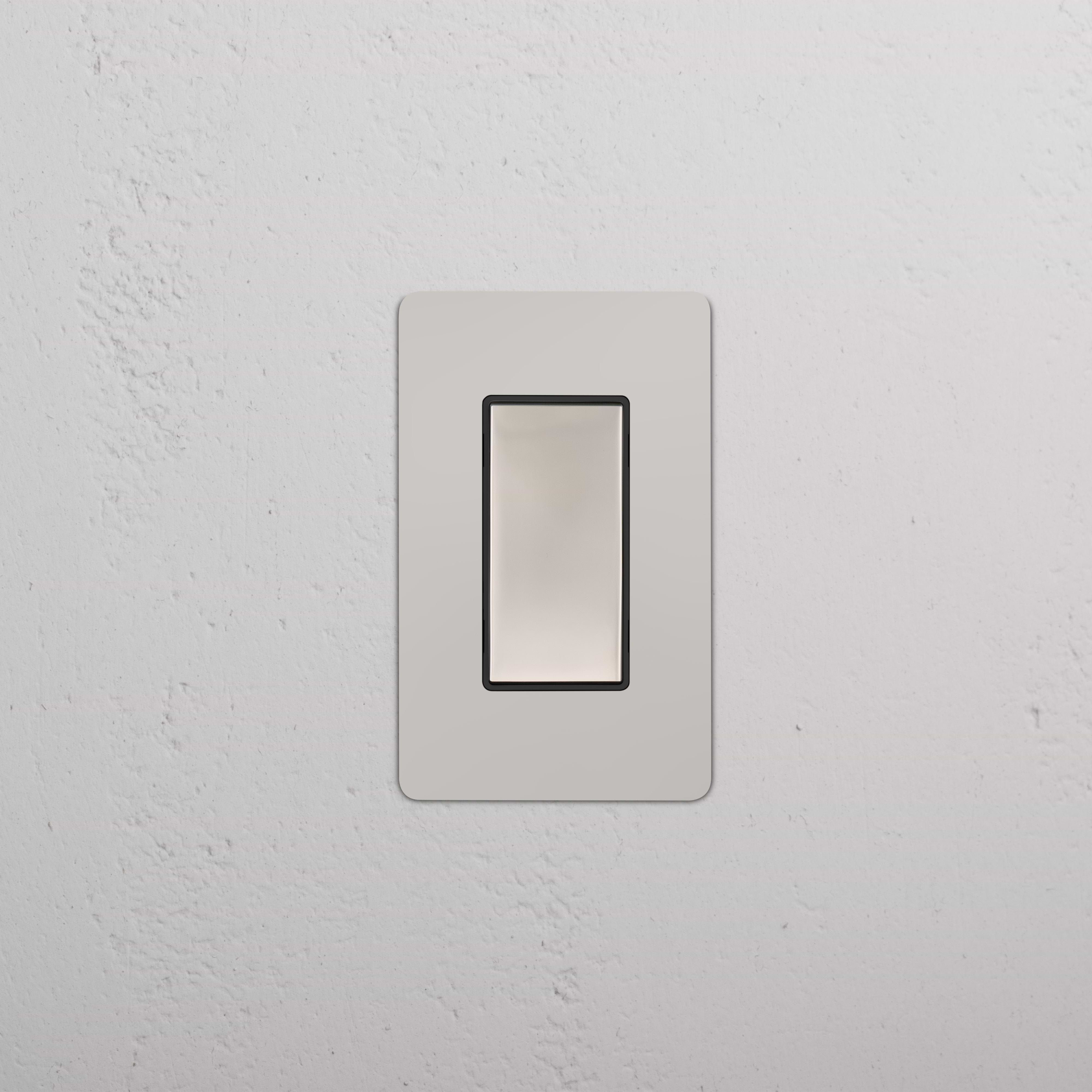 Kew 1G Center Retractive Rocker Switch in polished nickel black finish, mounted on a white wall.