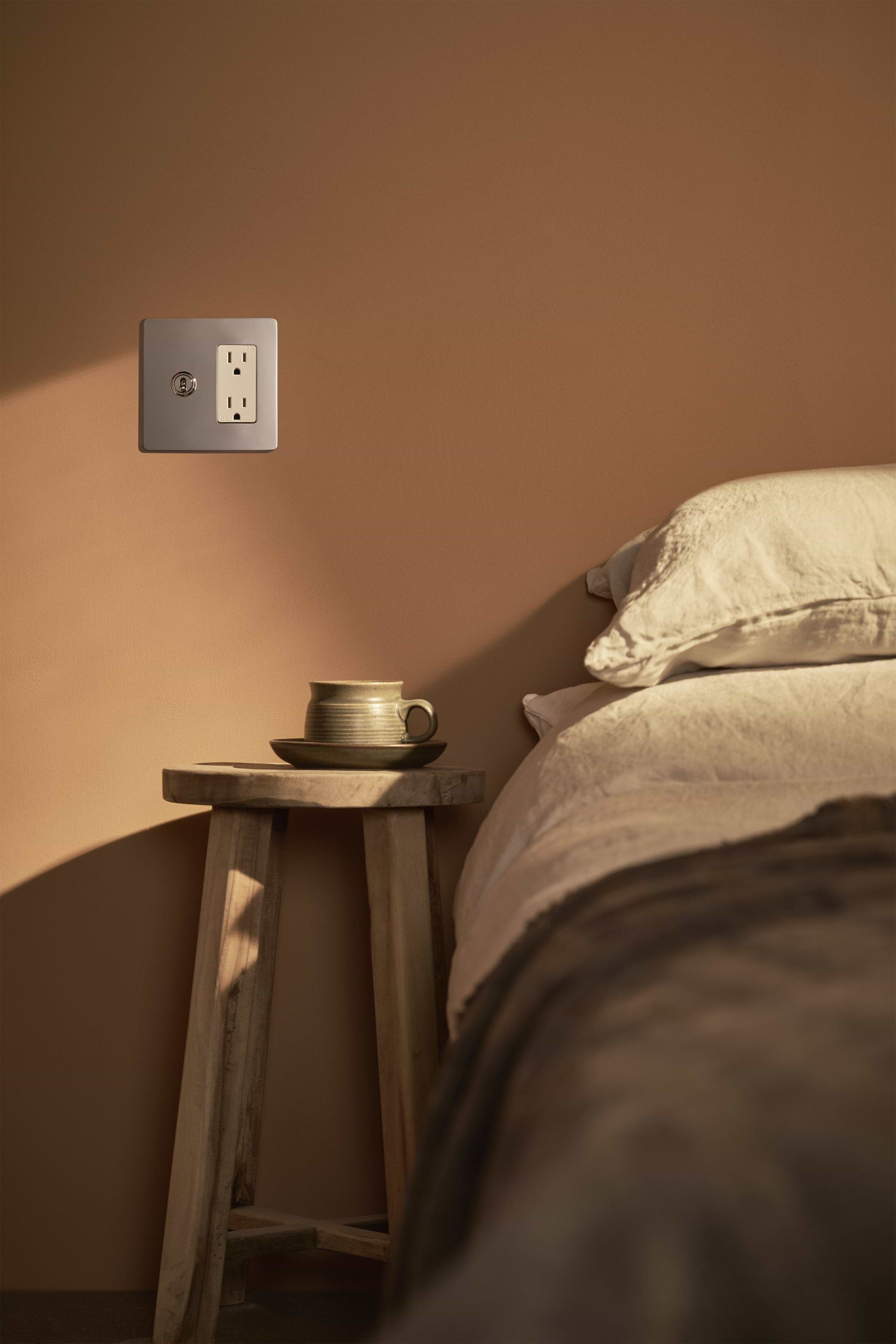 Kew 2G Toggle Switch & Outlet in polished nickel and white finish mounted on a beige wall.