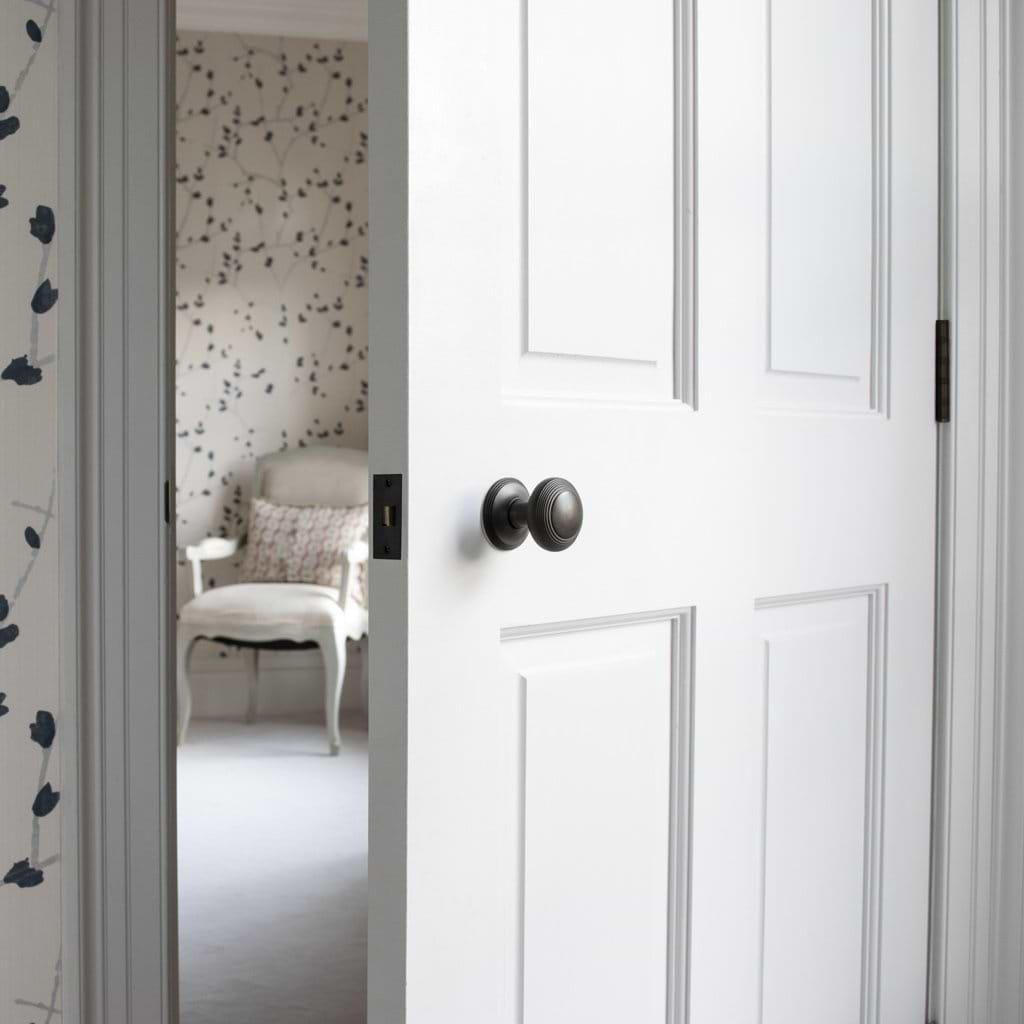 Bronze Poplar Passage Door Knob Set installed on a white door, partially open to show room interior.