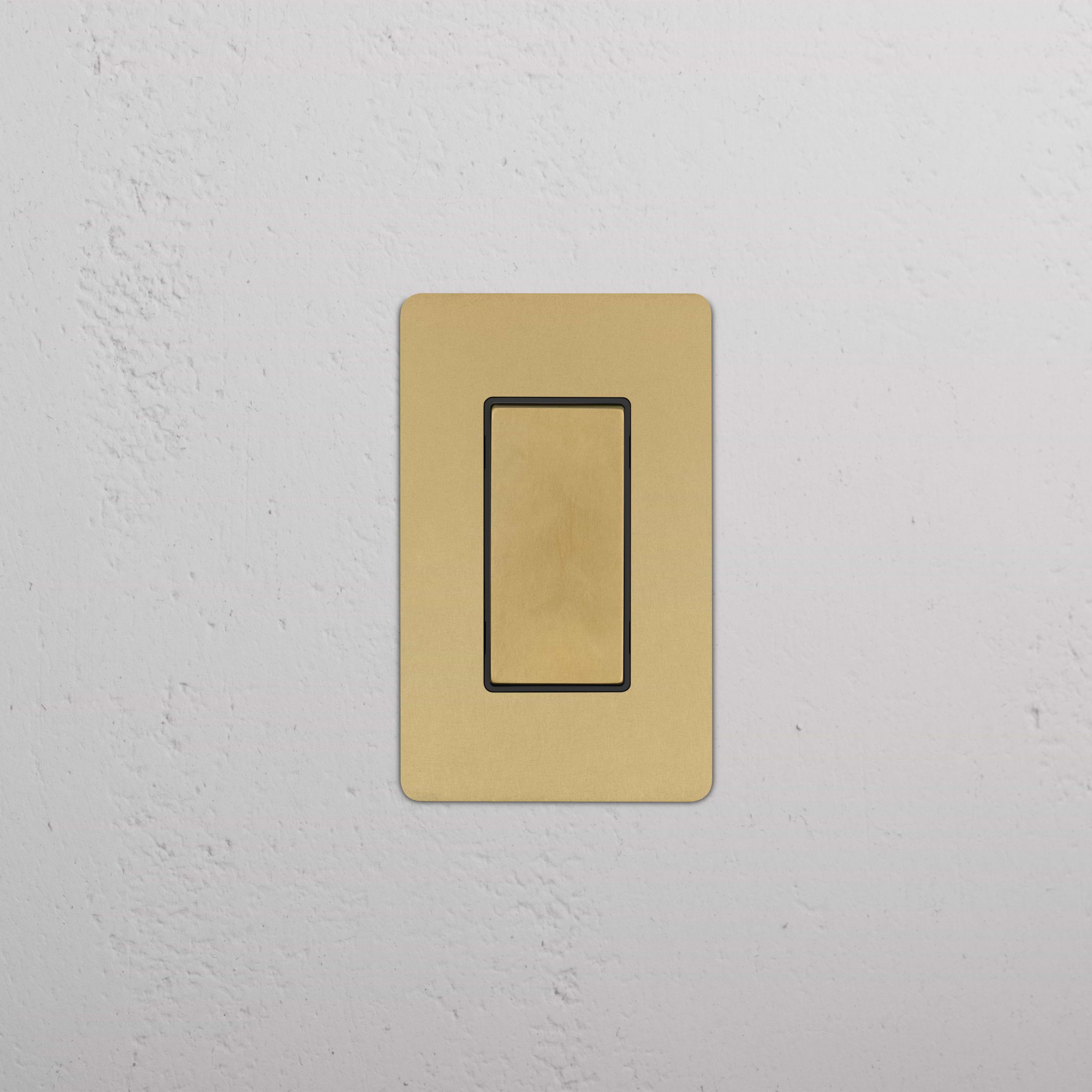 Kew 1G Center Retractive Rocker Switch in antique brass with black detailing, mounted on a wall.