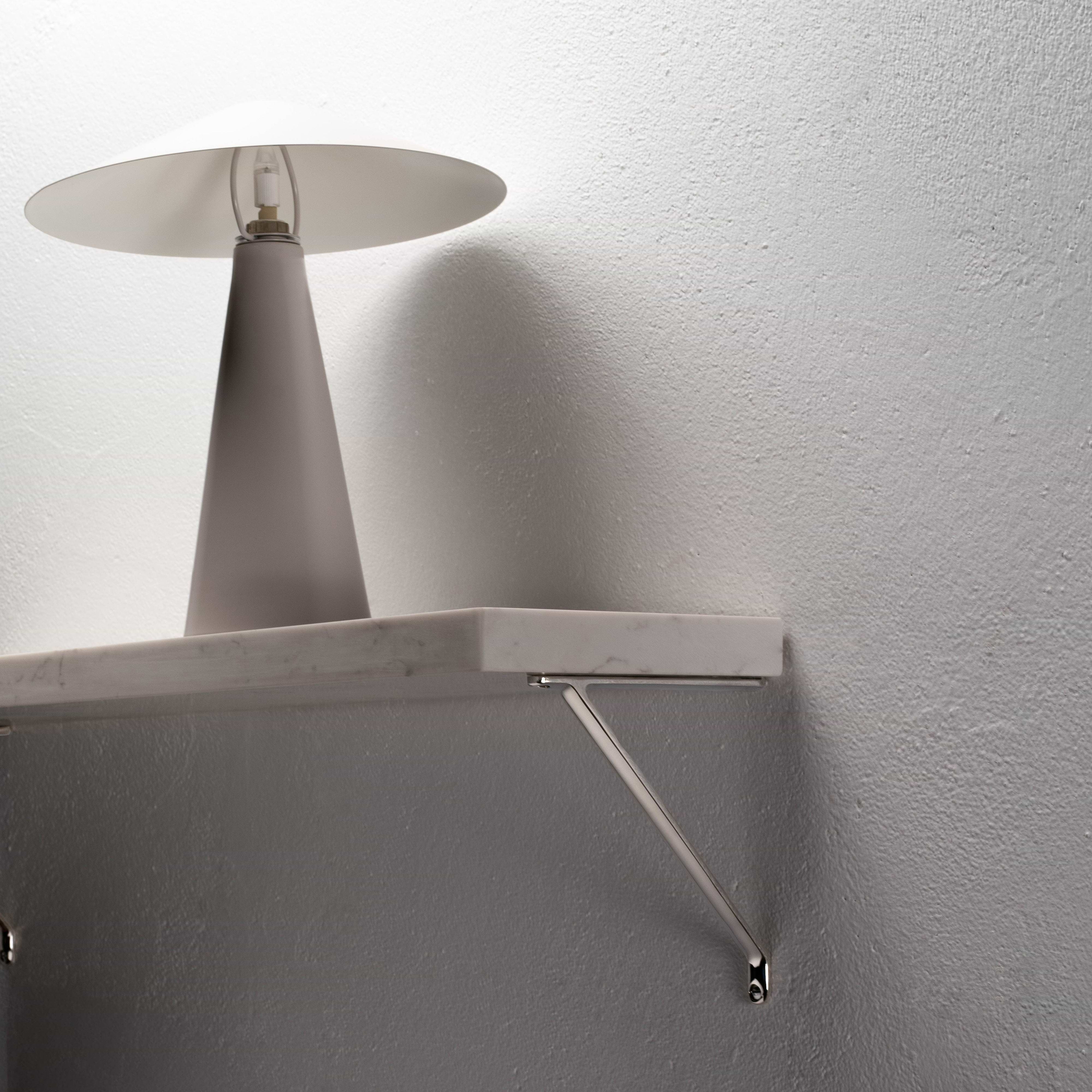 Small polished nickel Brixton shelf bracket mounted on a wall, supporting a white marble shelf.